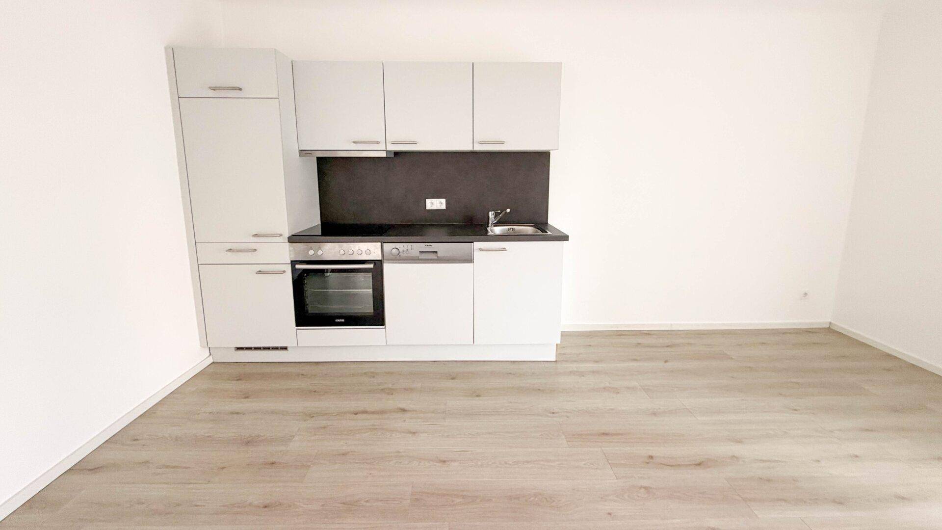 Helle Küche mit integrierter Küchenzeile, modernen Geräten und Laminatboden.