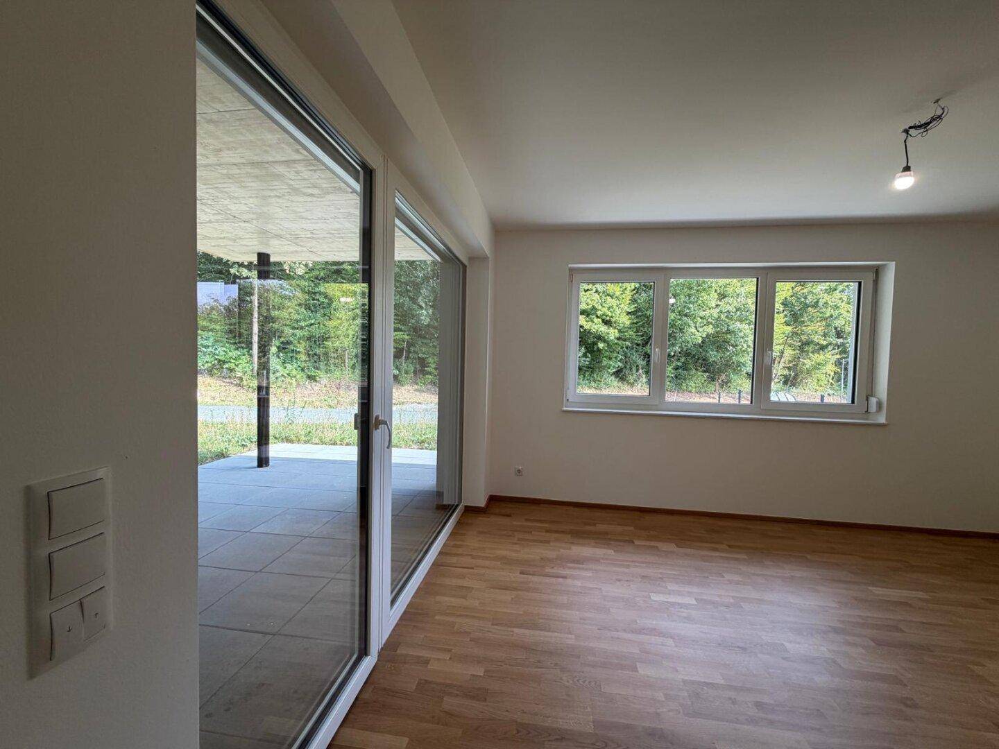 Lichtdurchfluteter Wohnbereich mit großen Schiebetüren zur Terrasse und Grünblick.