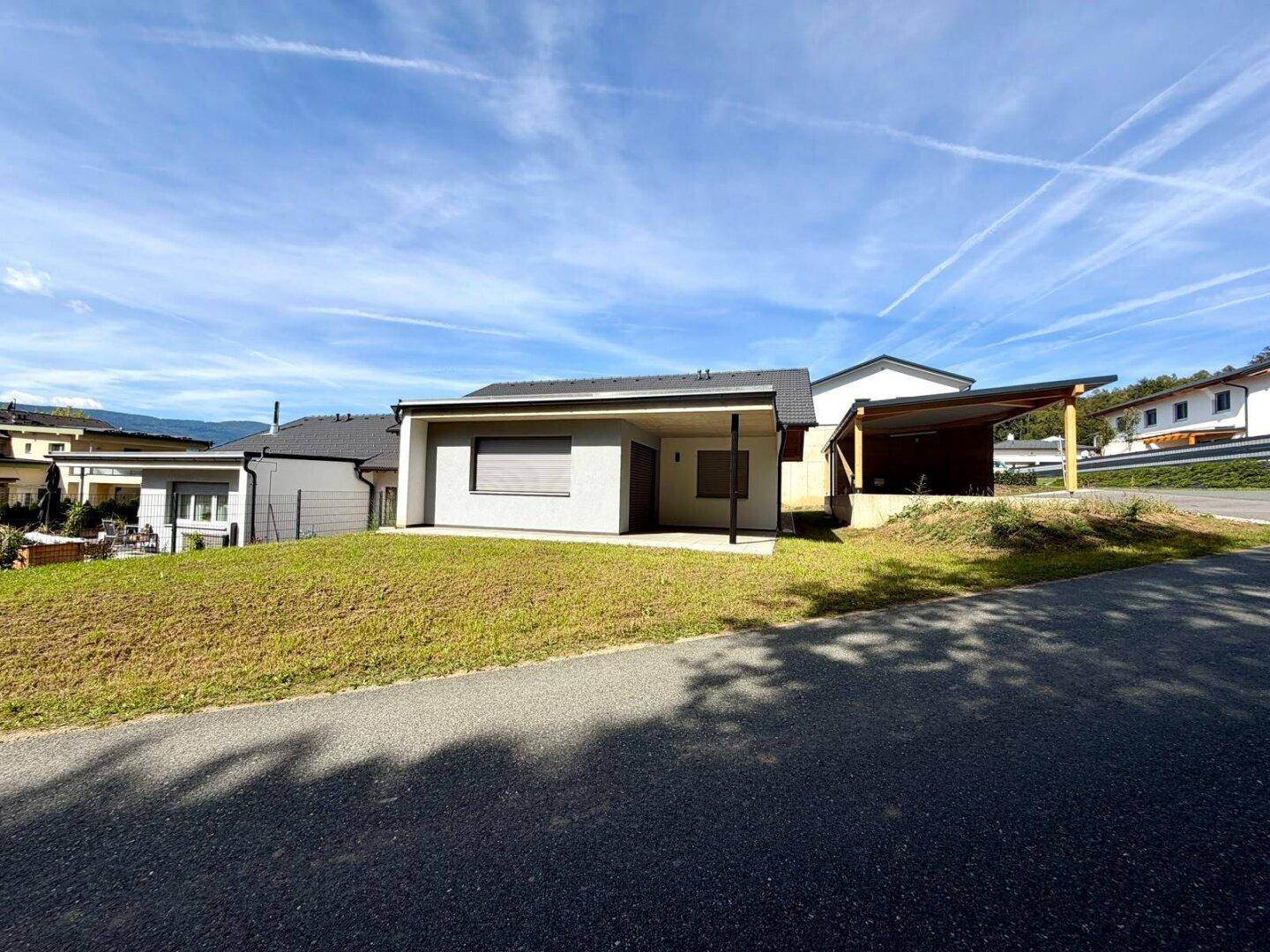 Frontansicht des Hauses mit Einfahrt, Carport und gepflegter Rasenfläche.