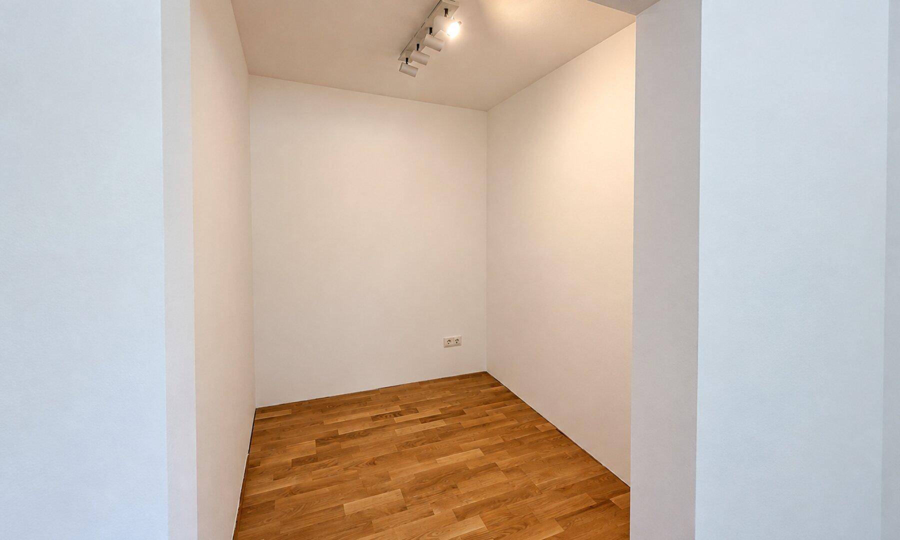 Kleiner Abstellraum mit Holzboden und Deckenbeleuchtung, ideal für zusätzlichen Stauraum.