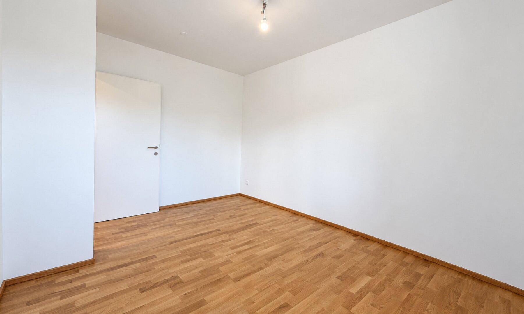 Geräumiges Schlafzimmer mit Holzboden und weiß gestrichenen Wänden, bereit zum Einzug.