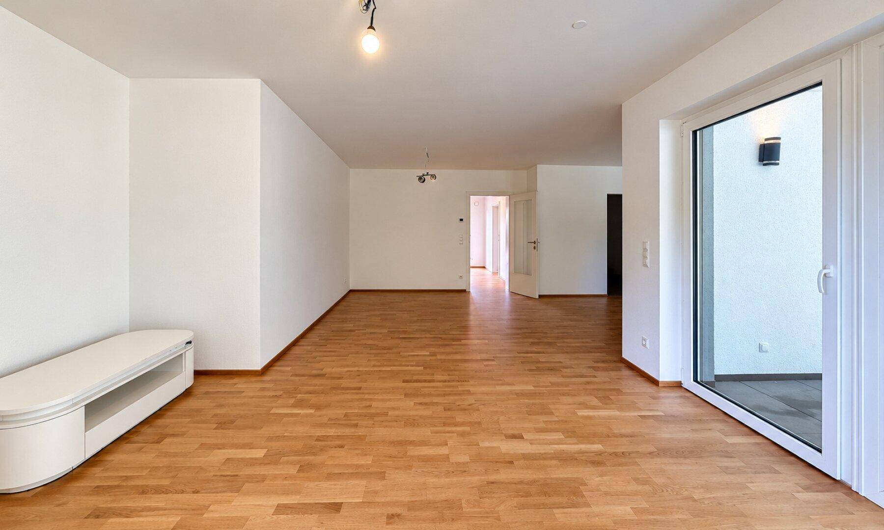 Offener Wohnbereich mit Holzboden und Zugang zur Terrasse, ideal für geselliges Beisammensein.