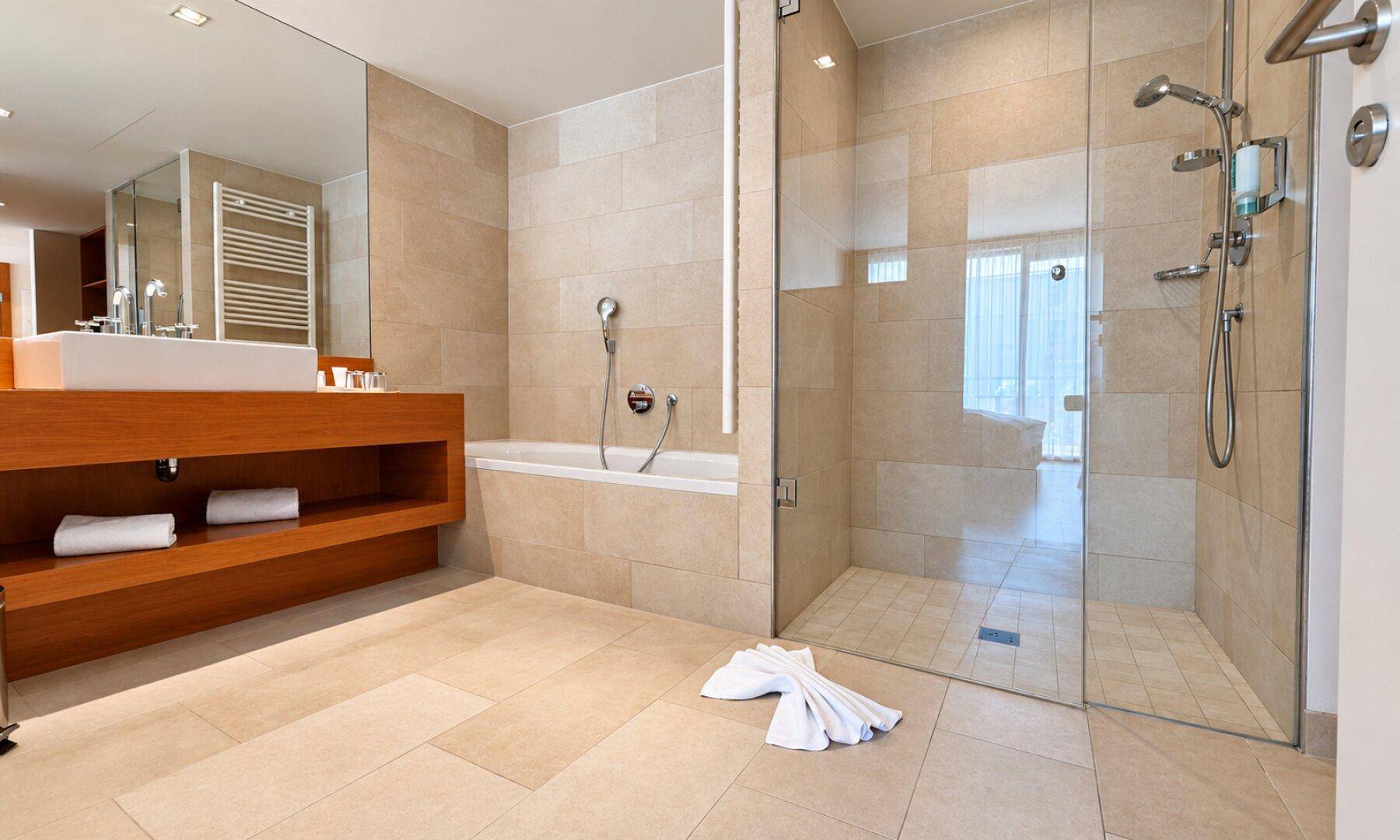 Modernes Badezimmer mit begehbarer Dusche, Badewanne und großformatigen Fliesen.