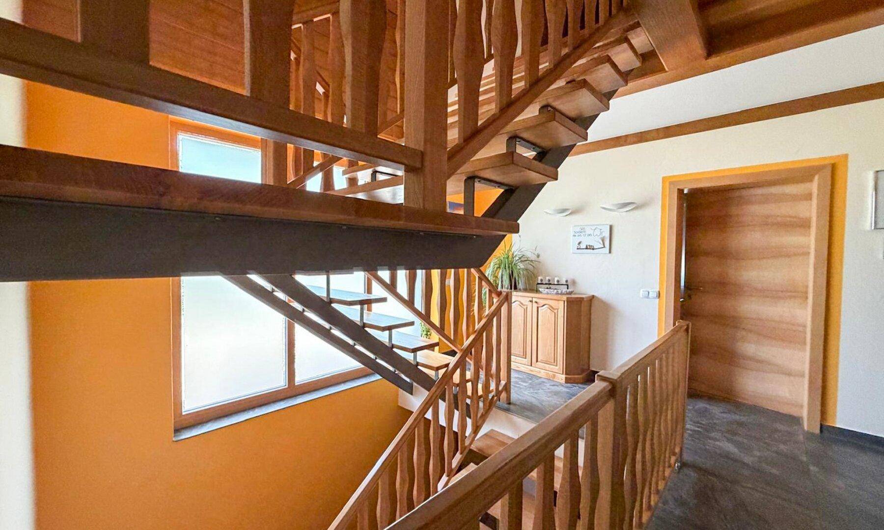 Heller Flur mit offener Holztreppe und Blick auf die obere Etage.