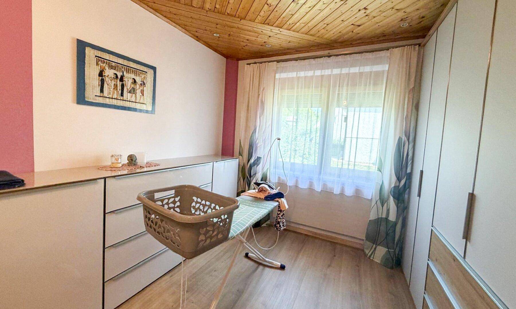 Praktischer Hauswirtschaftsraum mit Stauraum, Fenster und Bügelbrett.