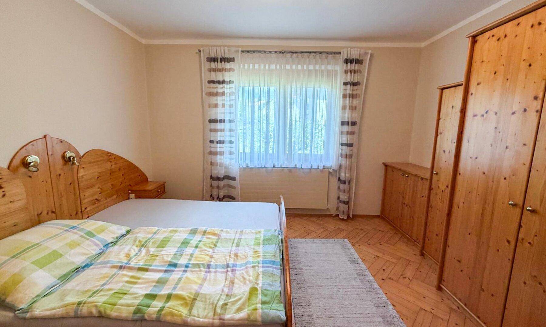 Schlafzimmer mit Doppelbett aus hellem Holz, Kleiderschränken und Parkettboden.