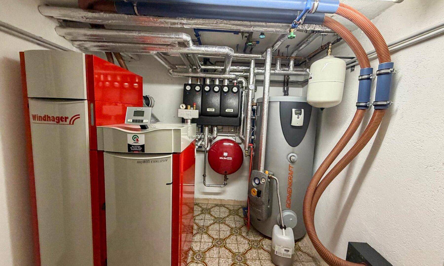 Heizungsraum im Keller mit modernen Heizungsanlagen und Warmwasserspeicher.