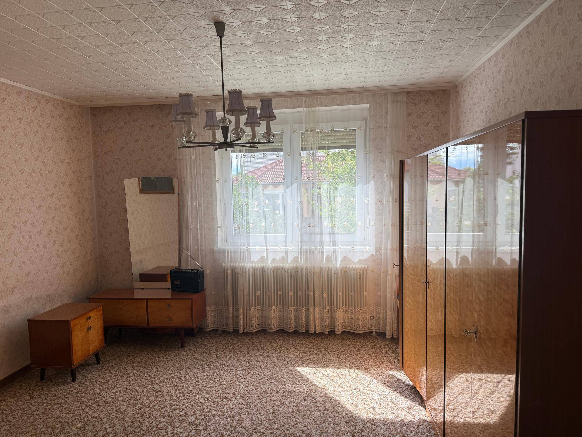 Geräumiges Schlafzimmer mit gemusterter Tapete und Decke, bereit zur individuellen Gestaltung.