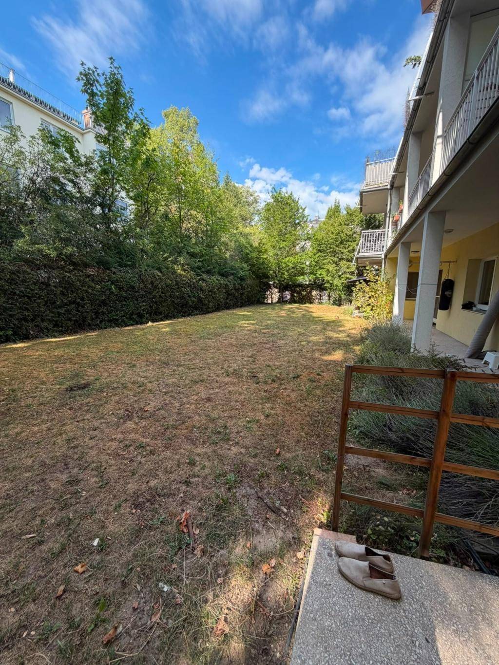 Großer Gartenbereich mit Rasenfläche und Bäumen neben dem Wohngebäude.