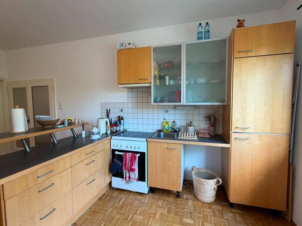 Funktionale Küche mit Holzschränken, Herd, Spüle und Kühlschrank, ausgestattet für den täglichen Gebrauch.