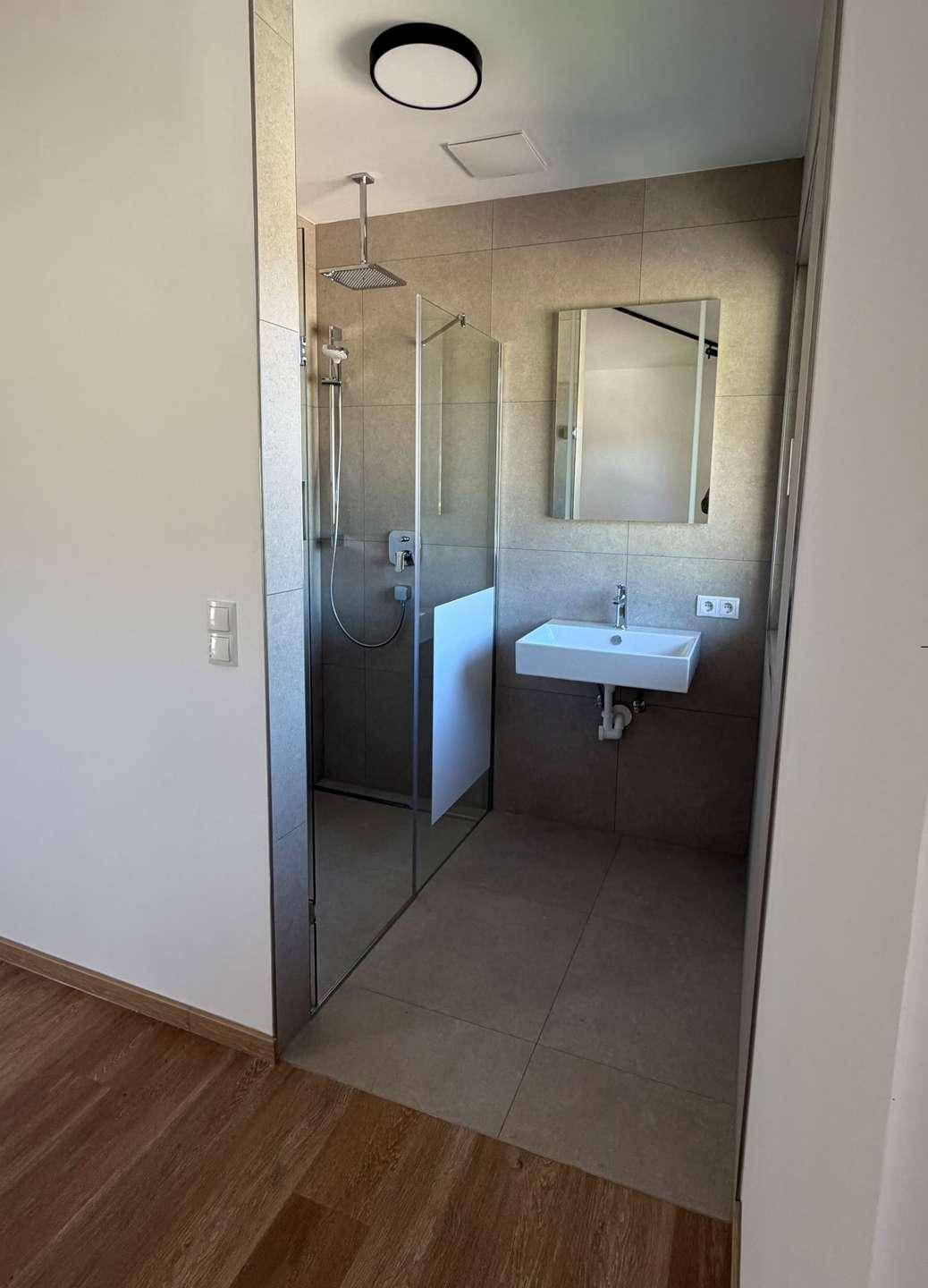 Modernes Badezimmer mit ebenerdiger Dusche, Wandfliesen und minimalistischem Waschbecken.