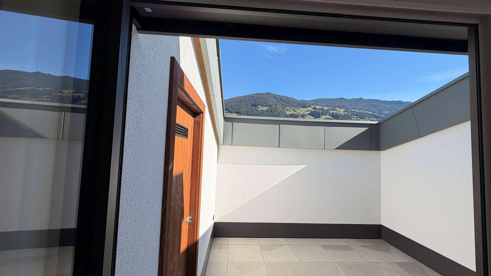 Sonnige Terrasse mit Fliesenboden und weitem Blick auf die umliegende Berglandschaft.