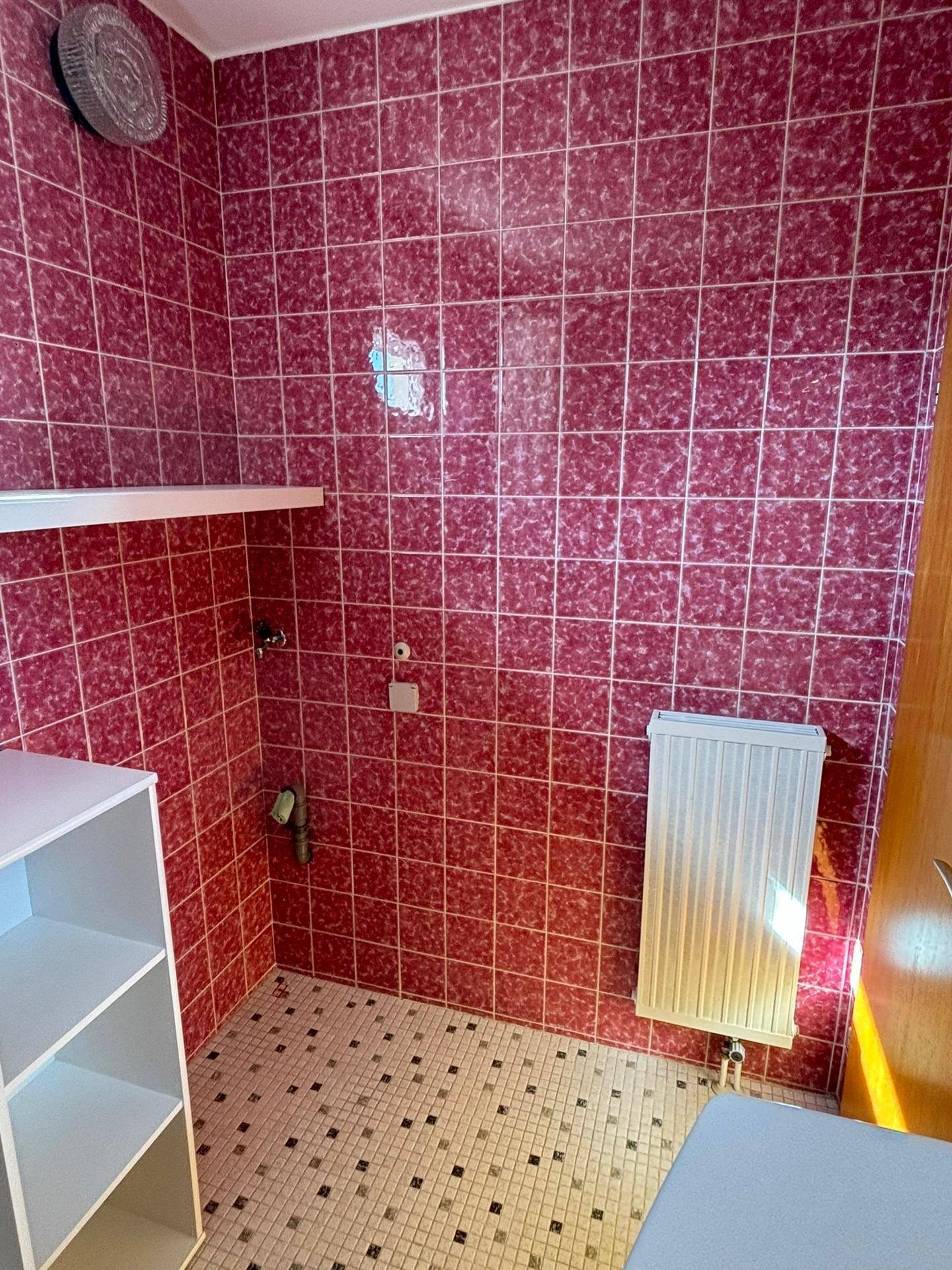 Badezimmer mit roten Fliesen und Heizkörper, das eine funktionale Ausstattung bietet.