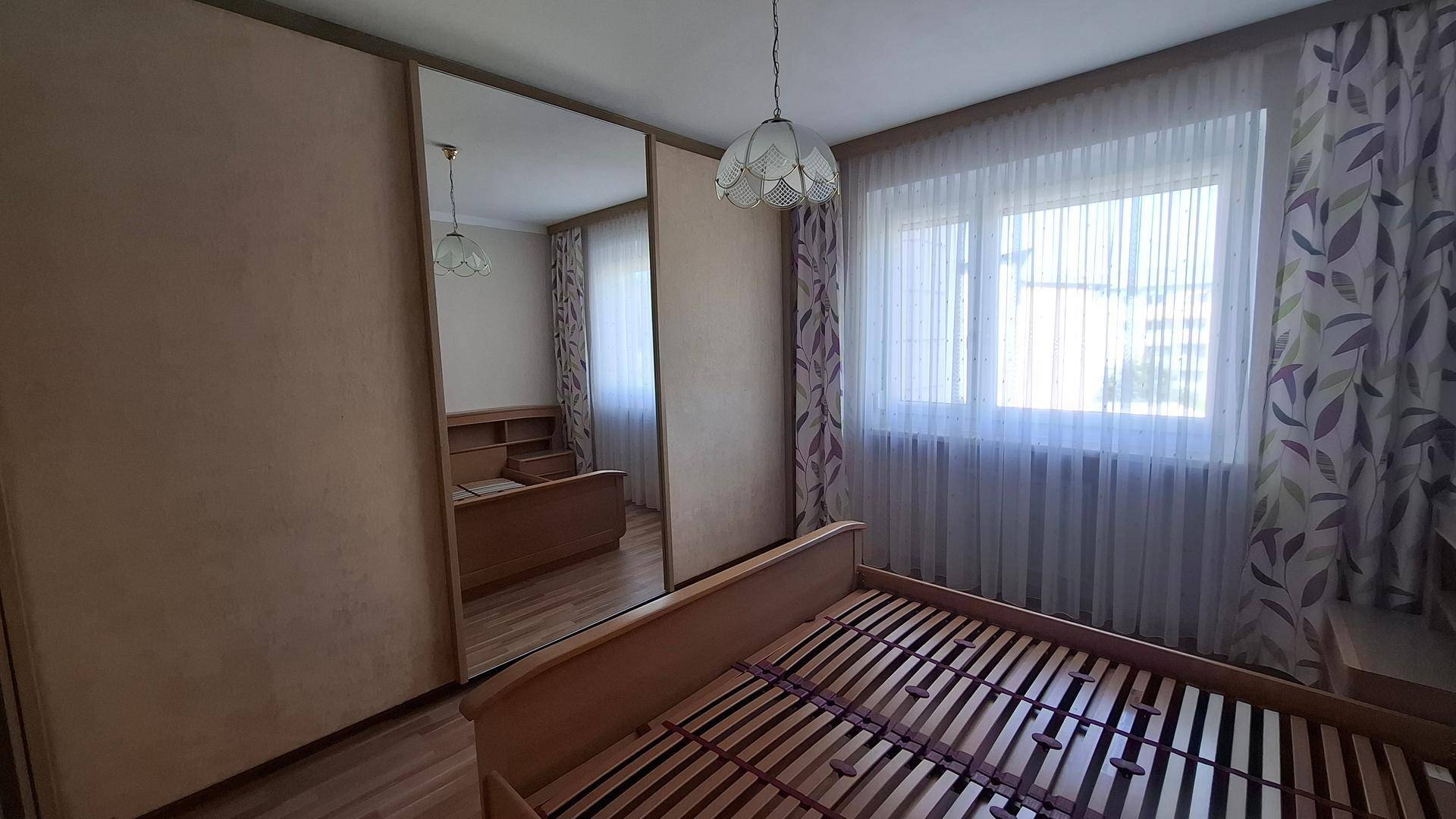 Schlafzimmer mit großem Spiegelschrank und Holzbett, das viel Stauraum bietet.