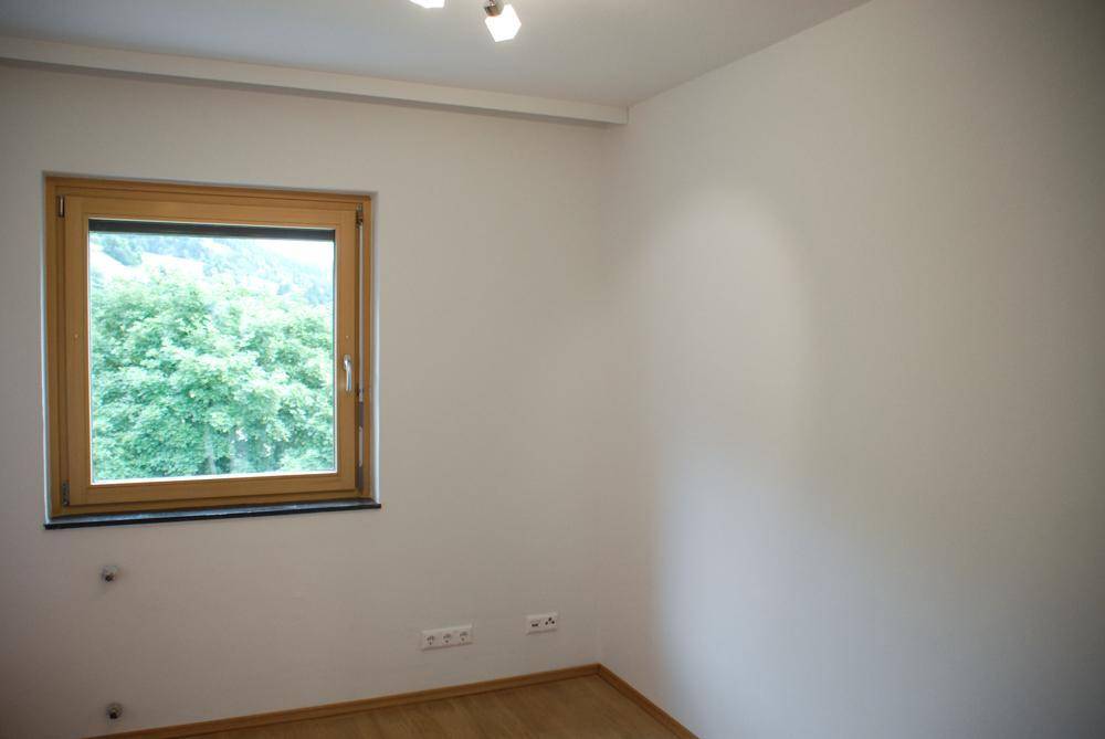Helles Zimmer mit Holzfußboden und einem Fenster mit Blick ins Grüne, ideal als Schlafzimmer.