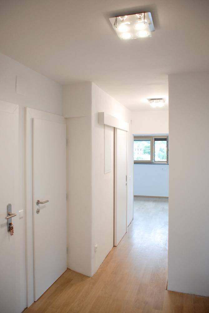 Geräumiger Flur mit hellem Holzfußboden und mehreren weißen Türen, die zu den Zimmern führen.