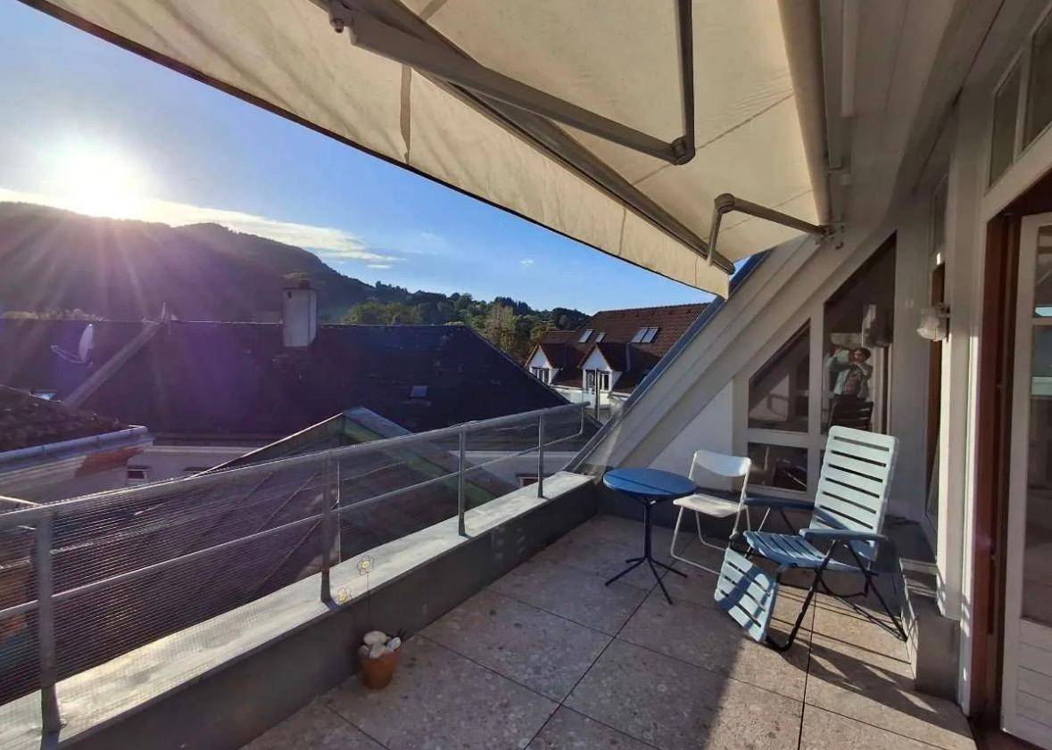 Geräumige Dachterrasse mit Markise, Sitzgelegenheiten und weitem Blick über die Dächer und Hügel.