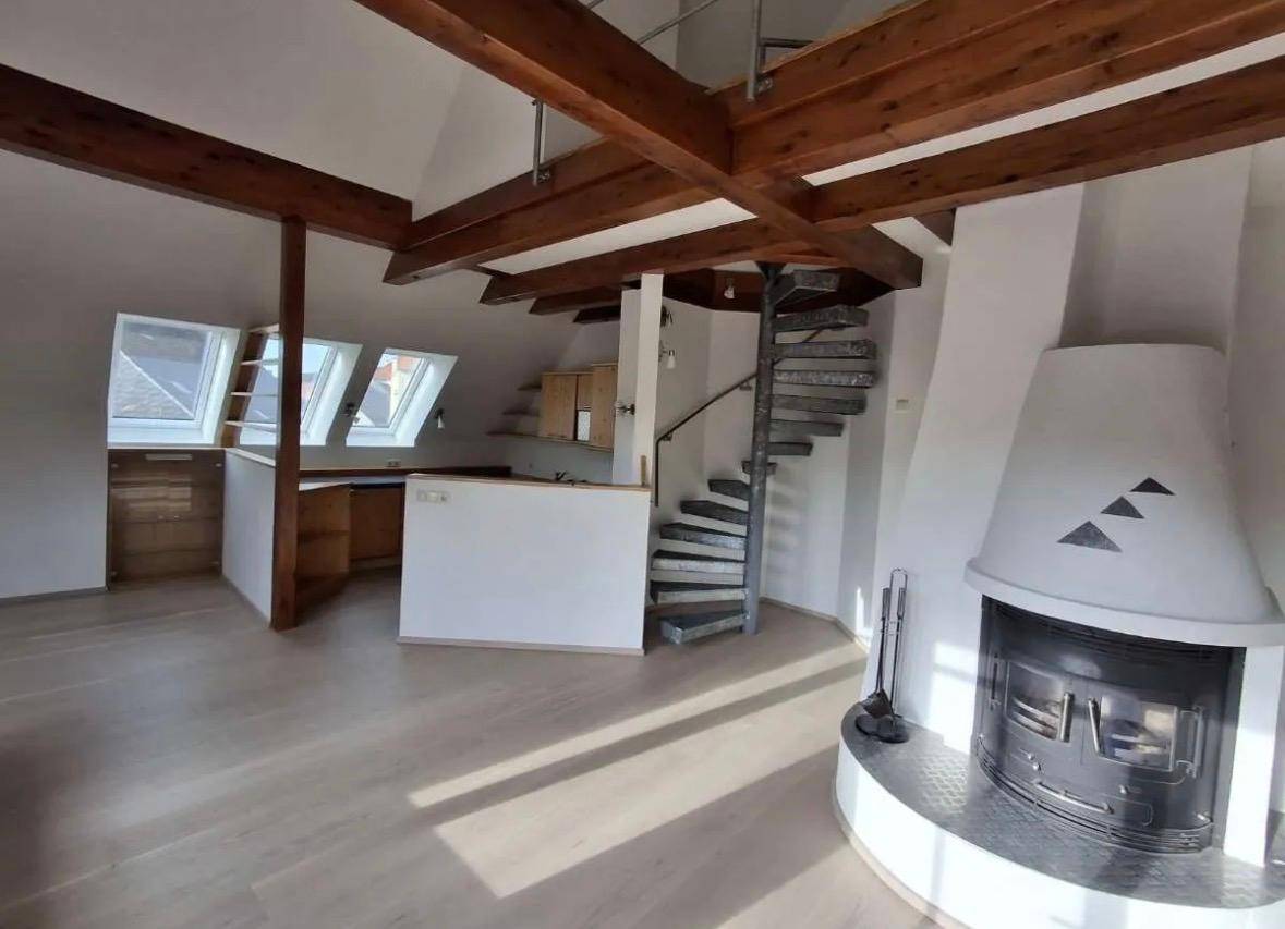 Geräumiger Wohnbereich mit Kamin, offener Küche und einer eleganten Wendeltreppe.
