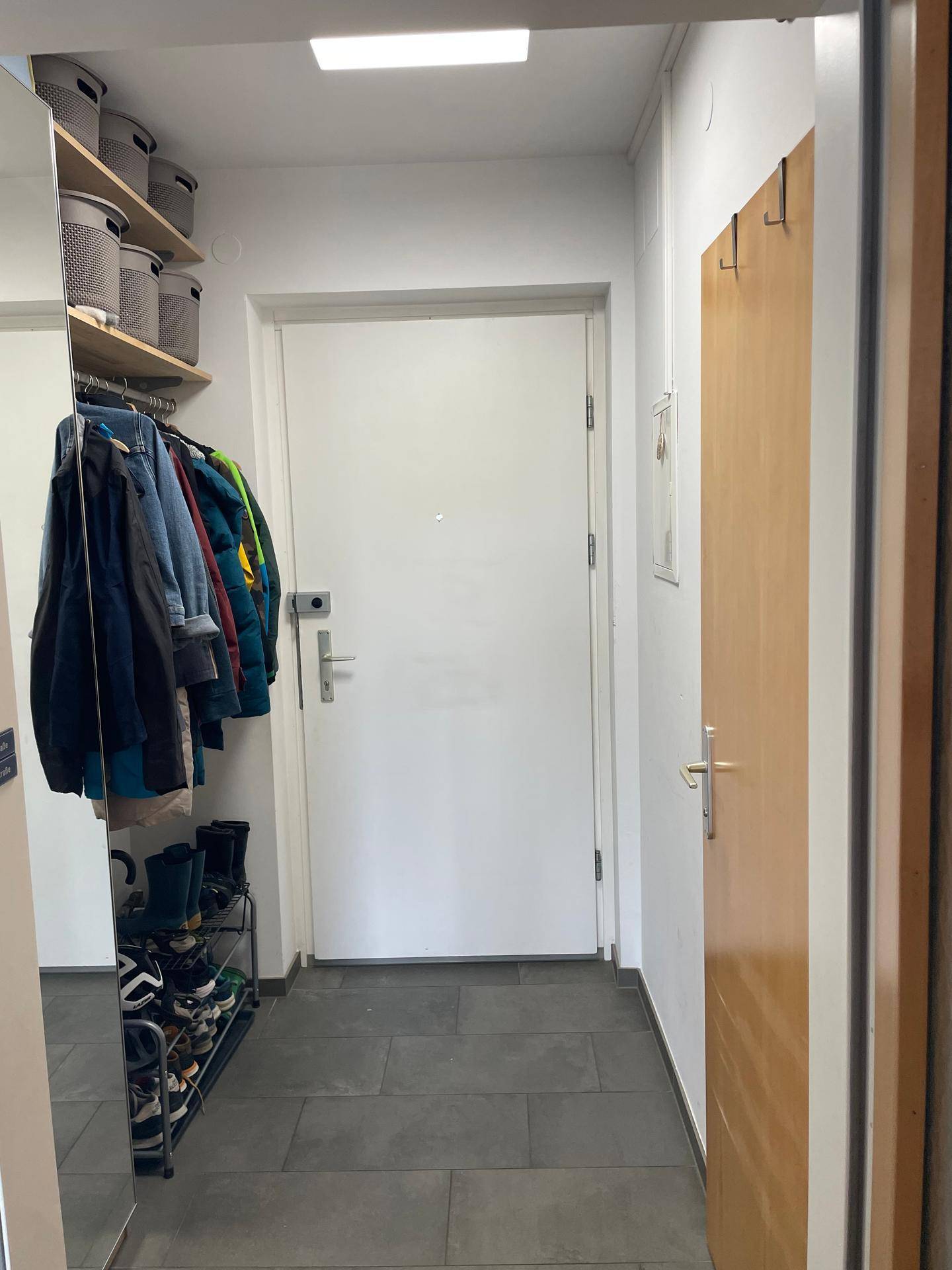 Eingangsbereich mit Fliesenboden, großem Spiegel, Garderobe und Schuhregal für praktische Aufbewahrung.