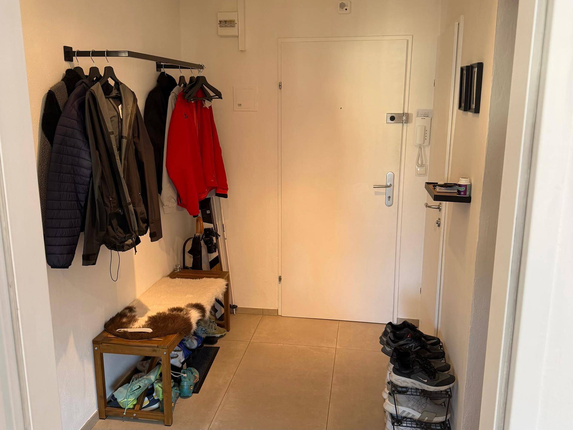 Eingangsbereich mit Fliesenboden, Garderobe und Schuhablage, funktional und hell.
