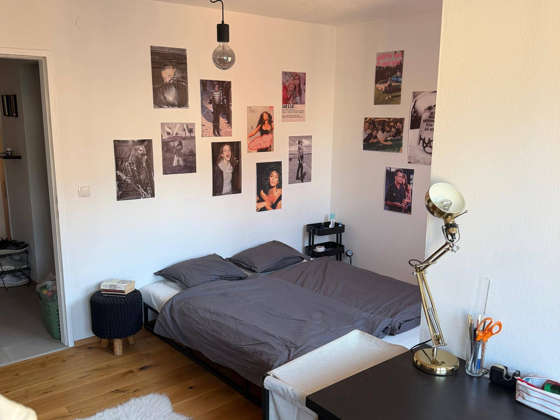 Schlafzimmer mit Holzboden, Doppelbett und Postern an der Wand, hell und funktional.