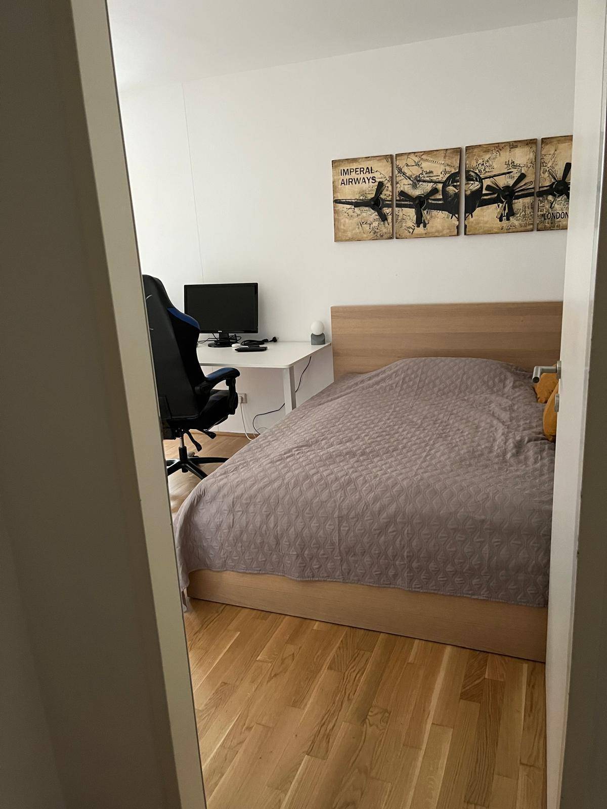 Schlafzimmer mit Holzbett, Schreibtisch und Gaming-Stuhl, ideal für Arbeit oder Freizeit.