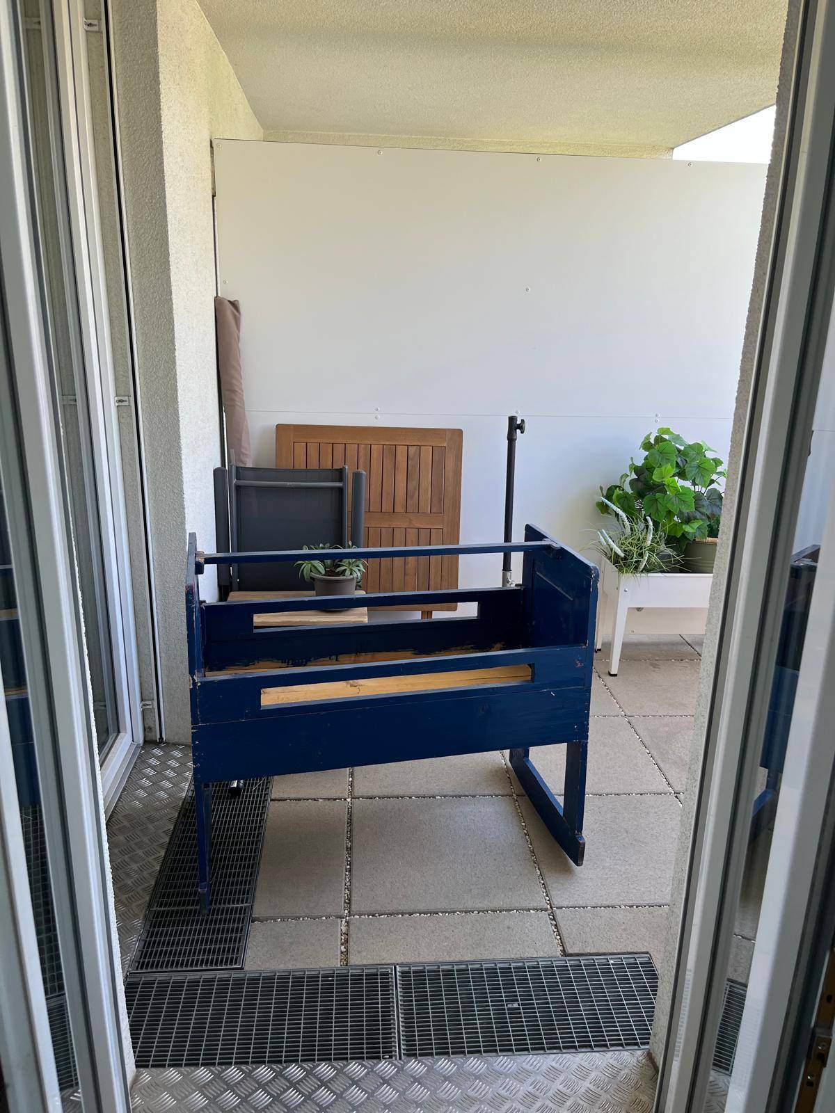 Balkon mit Fliesenboden und einem blauen Pflanzkasten, bereit für individuelle Gestaltung.