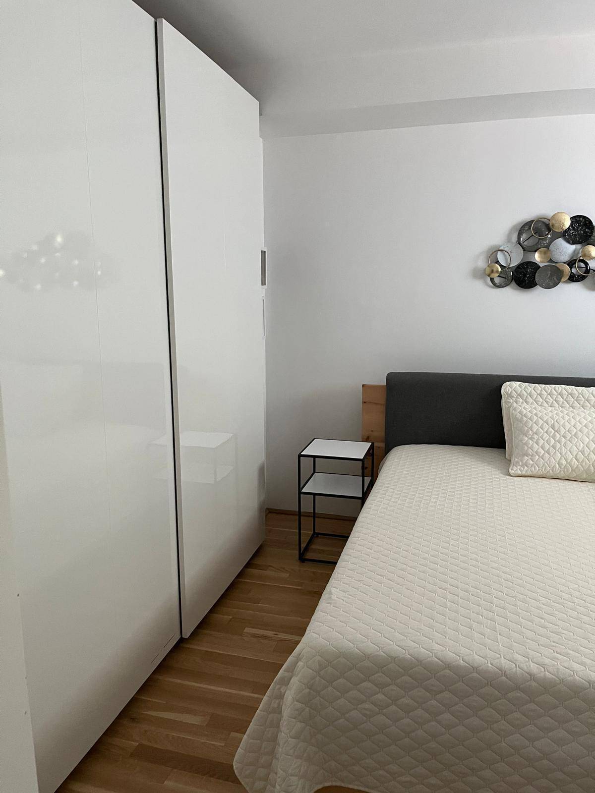 Schlafzimmer mit großem Kleiderschrank, Doppelbett und Holzboden, hell und funktional eingerichtet.