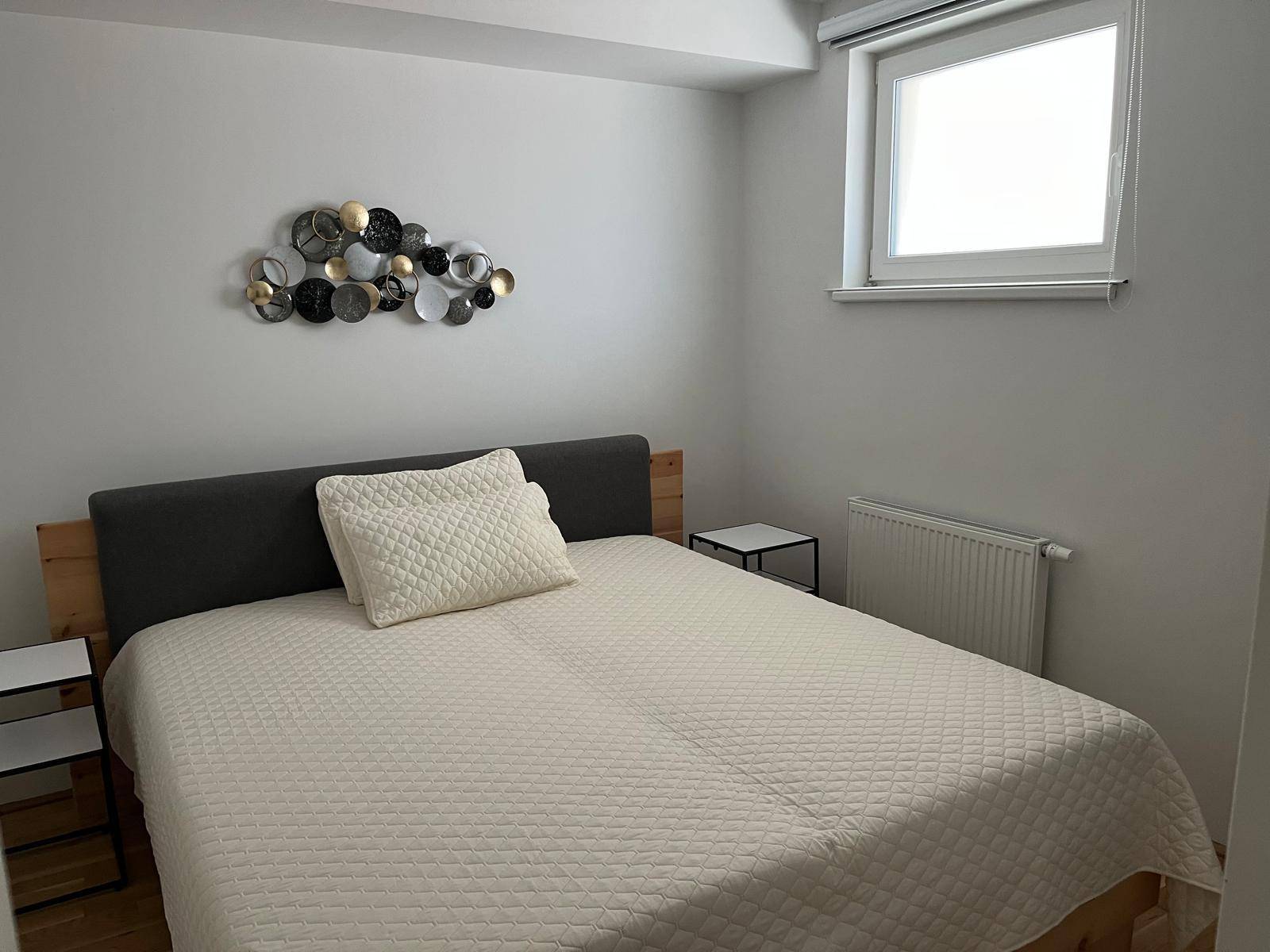 Schlafzimmer mit Doppelbett, Nachttischen und einem Fenster, das für natürliches Licht sorgt.