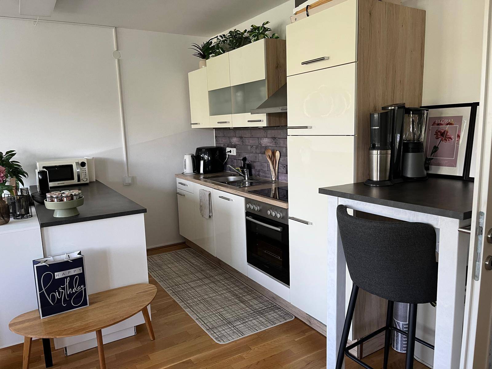 Moderne Einbauküche mit hellen Fronten, integrierten Geräten und einer kleinen Frühstücksbar.