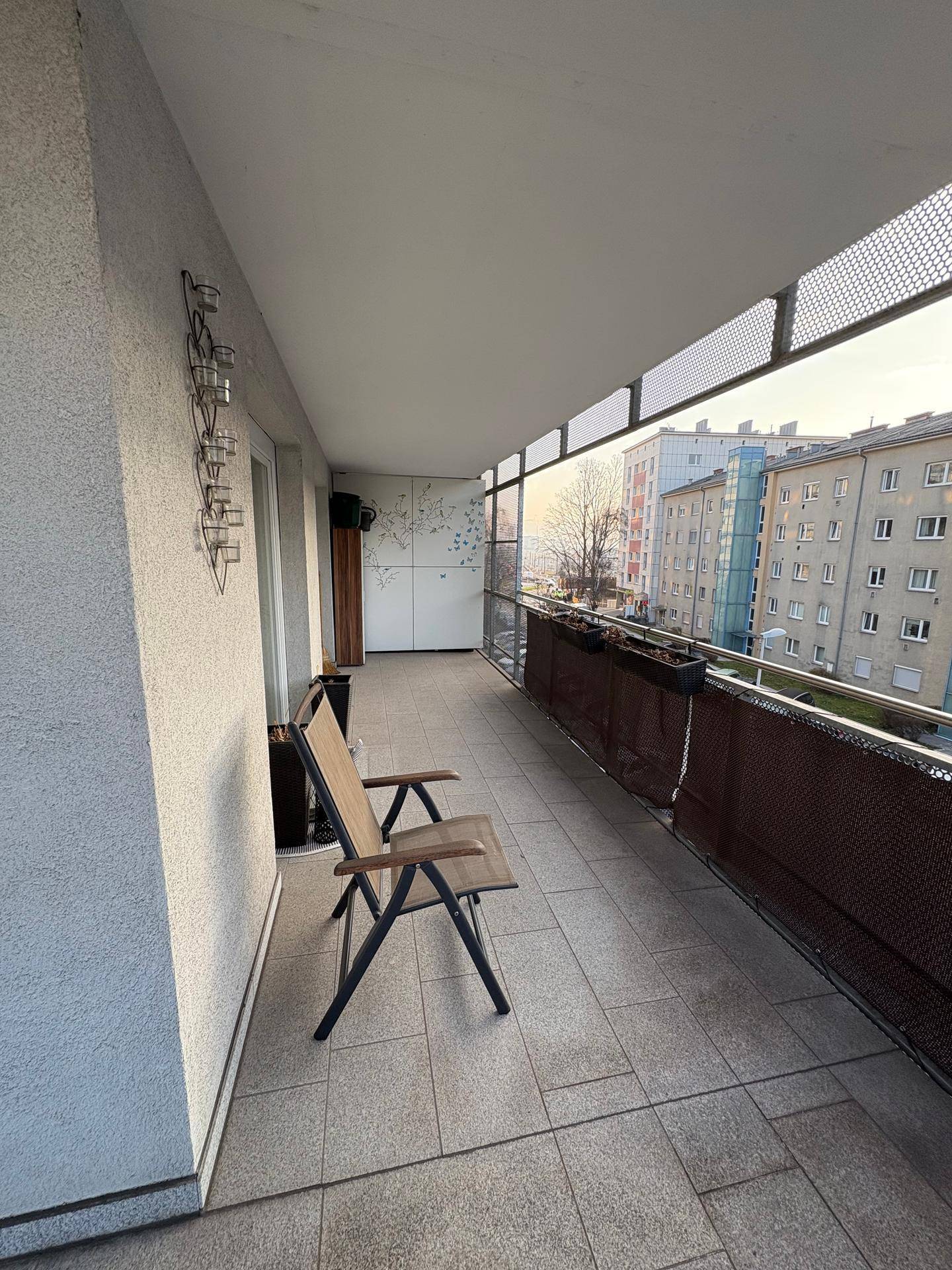 Geräumiger Balkon mit Fliesenboden und einem Stuhl, ideal zum Entspannen im Freien.