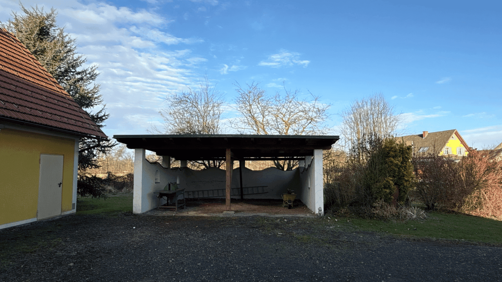 Überdachter Stellplatz oder Carport neben dem Haus, ideal für Fahrzeuge oder Lagerung.