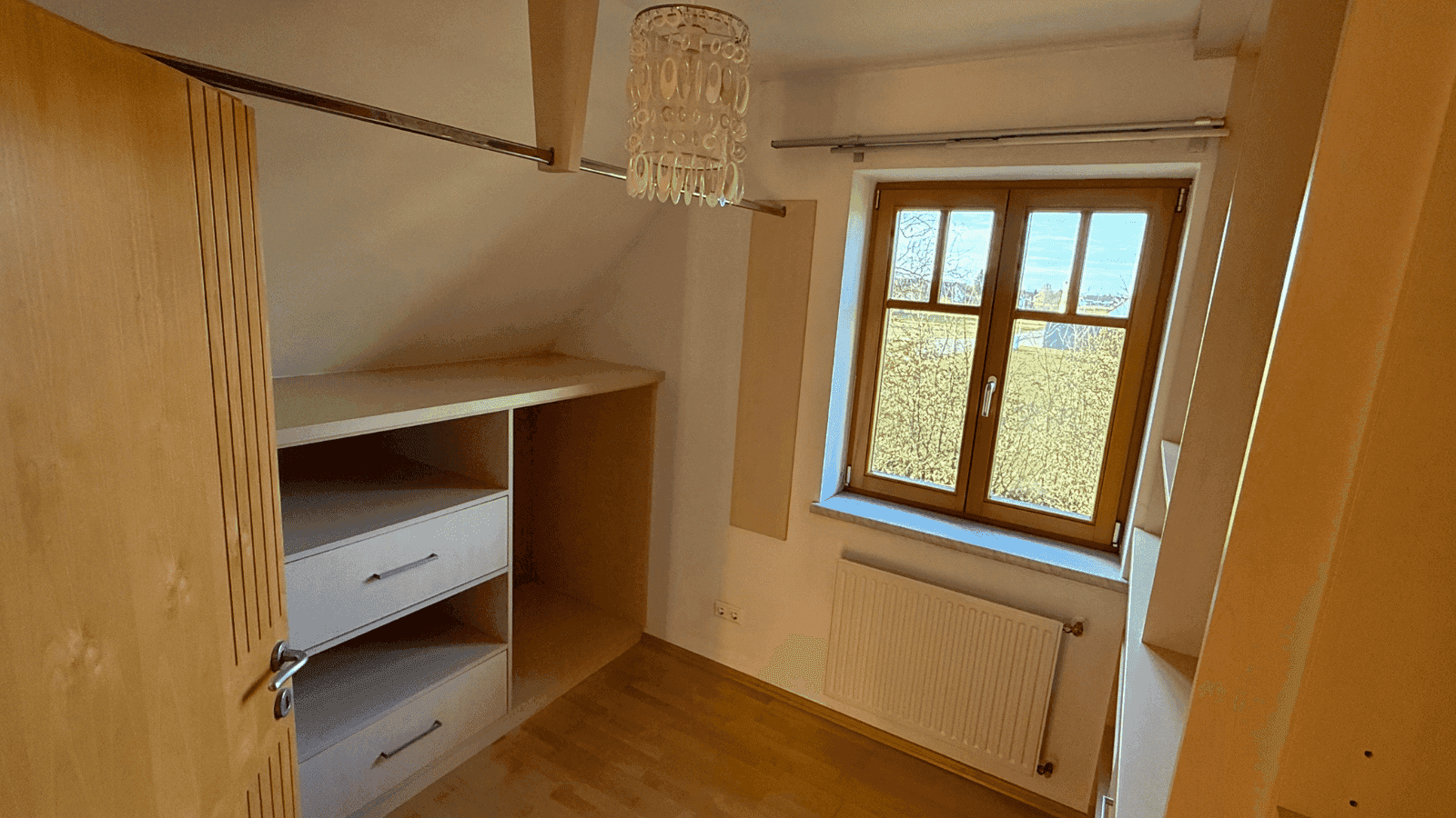 Praktischer begehbarer Kleiderschrank mit Einbauregalen und einem Fenster für Tageslicht.