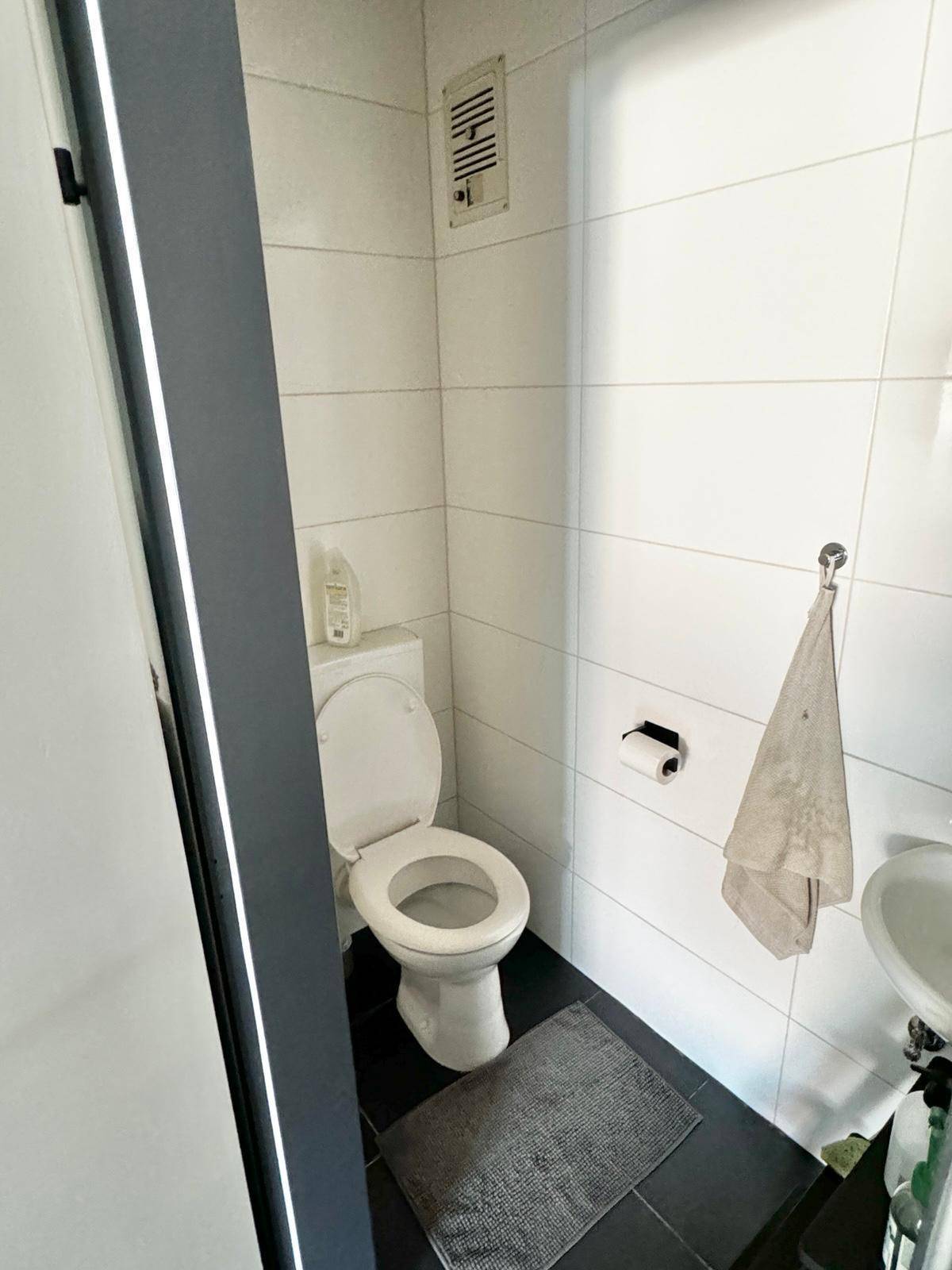 Kleines Gäste-WC mit Toilette, Waschbecken und weißen Wandfliesen.