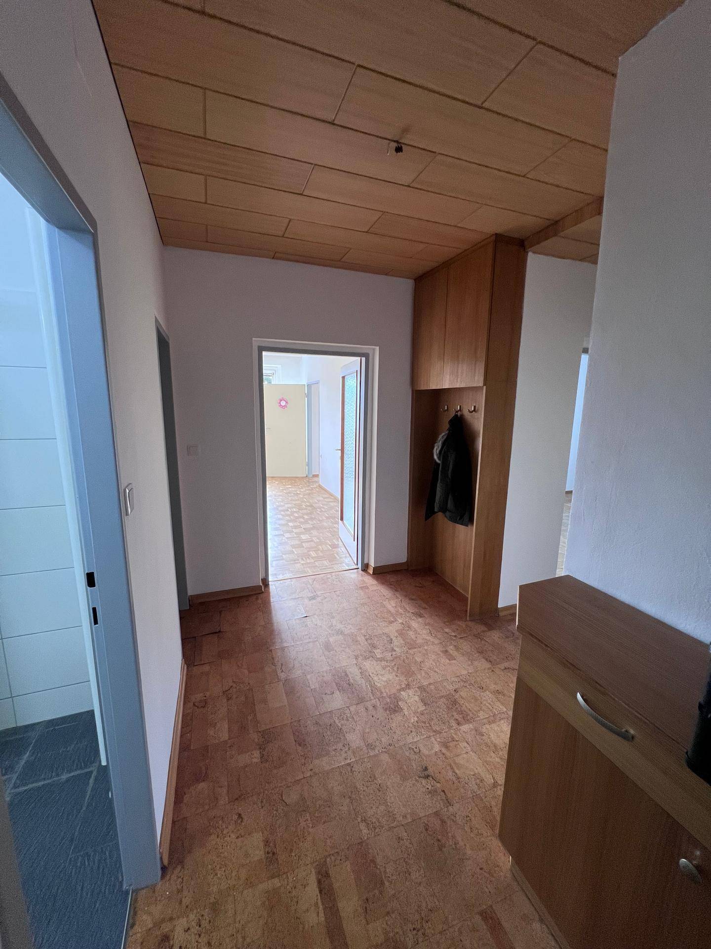 Geräumiger Flur mit Holzdecke, Parkettboden und integriertem Garderobenschrank, einladend und praktisch.