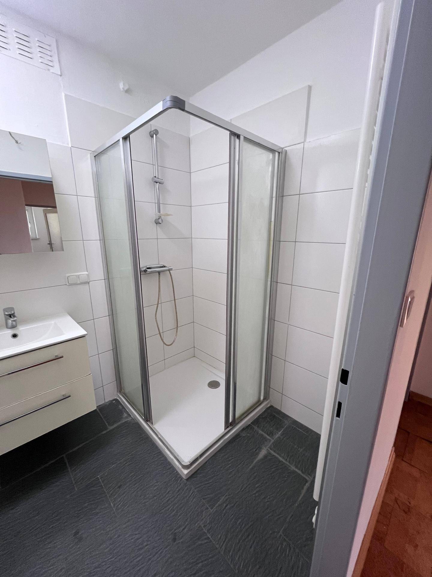 Moderne Duschkabine mit Glaswänden und Fliesenboden im Badezimmer, sauber und gepflegt.