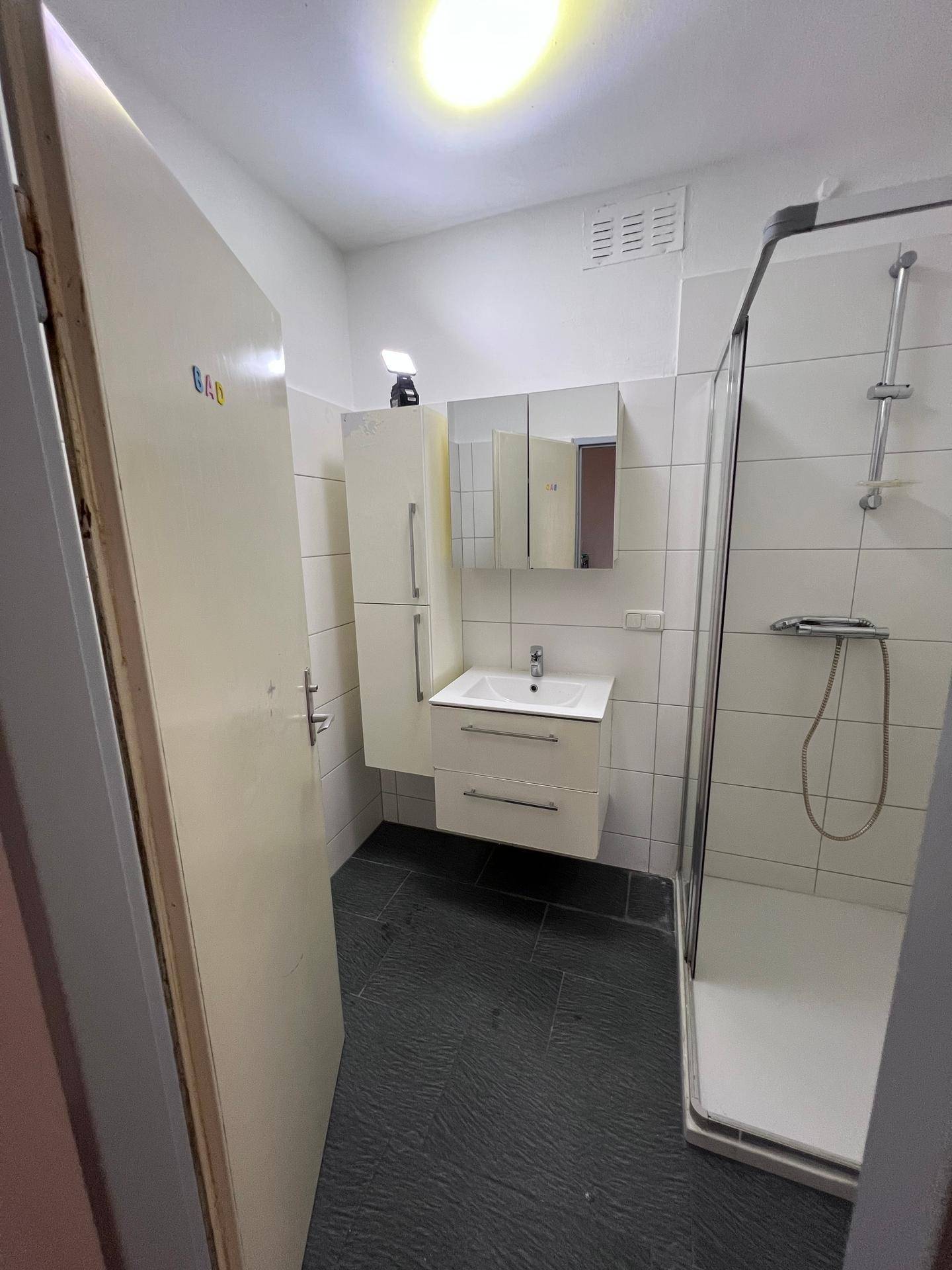 Badezimmer mit Duschkabine, Waschbecken und Spiegelschrank, in gutem Zustand und funktional eingerichtet.