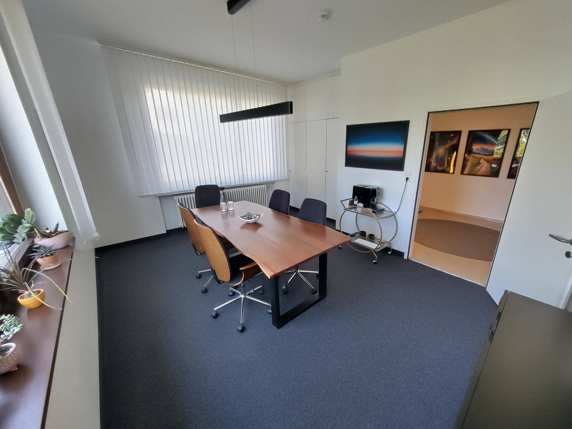 Geräumiges Büro mit großem Fenster, Jalousien und Pflanzen auf der Fensterbank.
