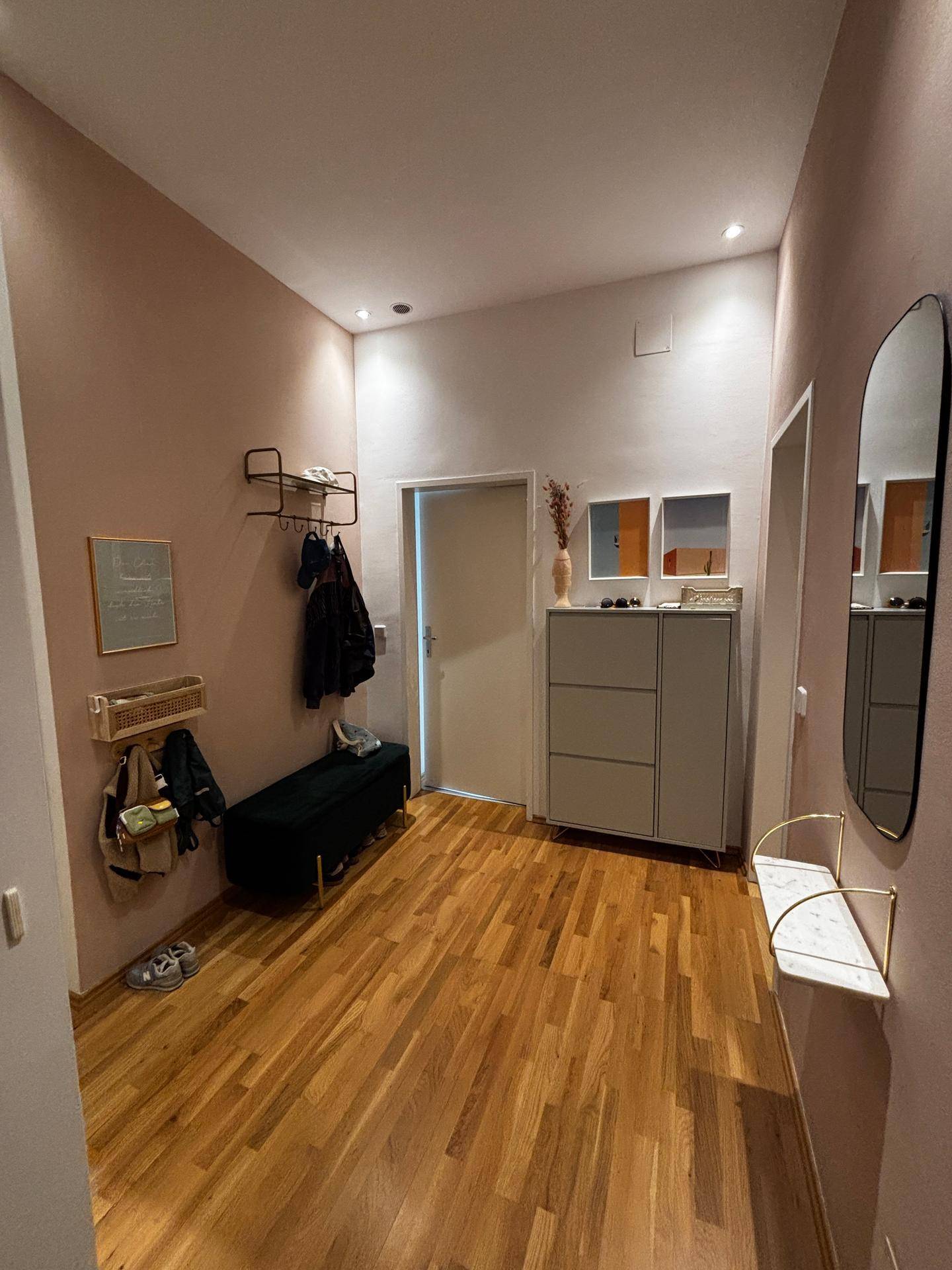 Heller Flur mit Holzboden, Garderobe und Schuhschrank.