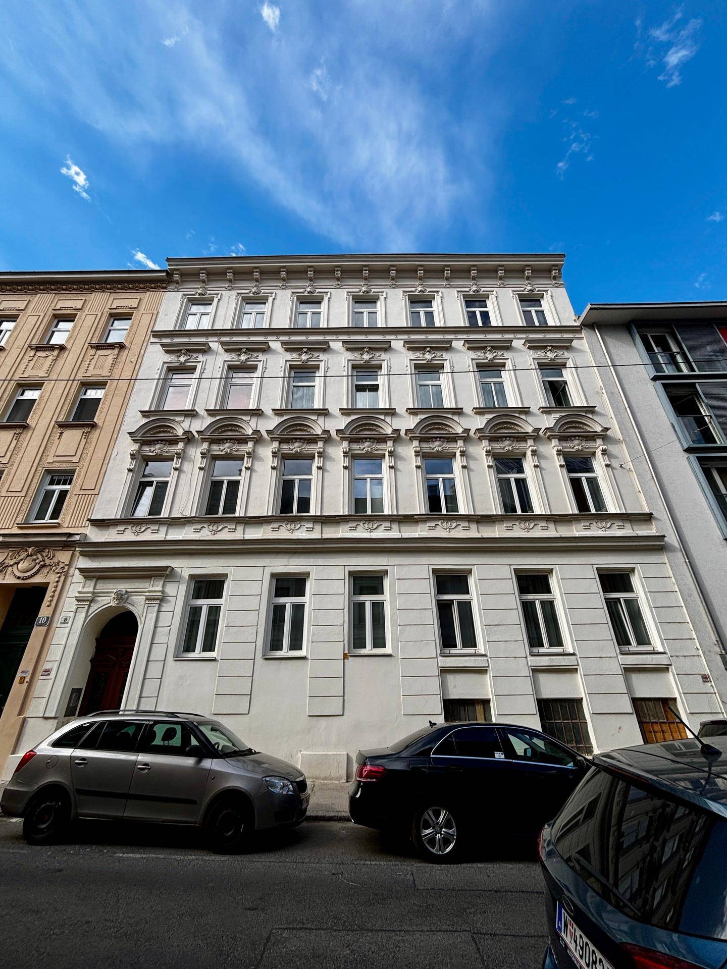 Klassische Fassade eines Mehrfamilienhauses mit vielen Fenstern und architektonischen Details.