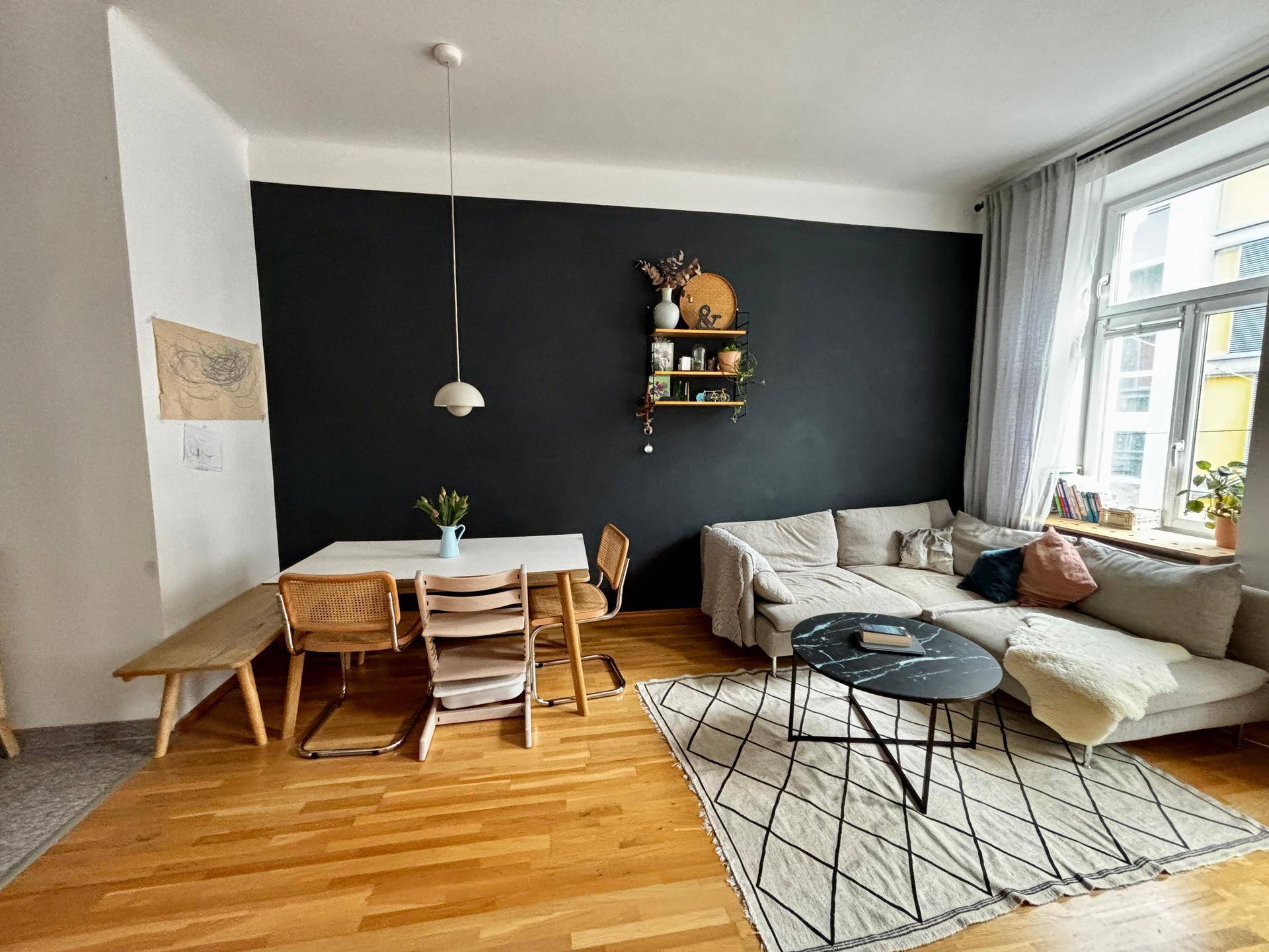 Offener Wohn- und Essbereich mit Holzboden, Esstisch und gemütlichem Sofa.