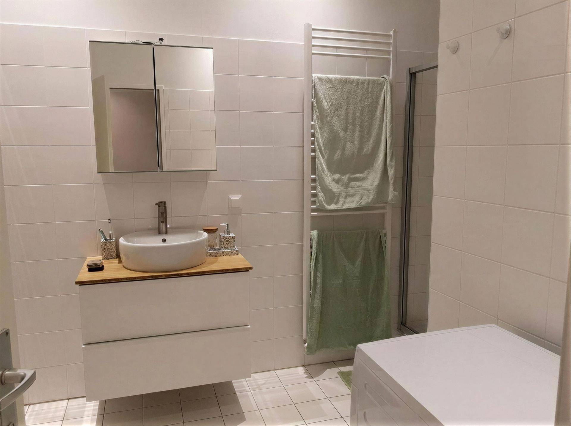 Modernes Badezimmer mit weißem Waschbecken, Fliesen und beheiztem Handtuchhalter.