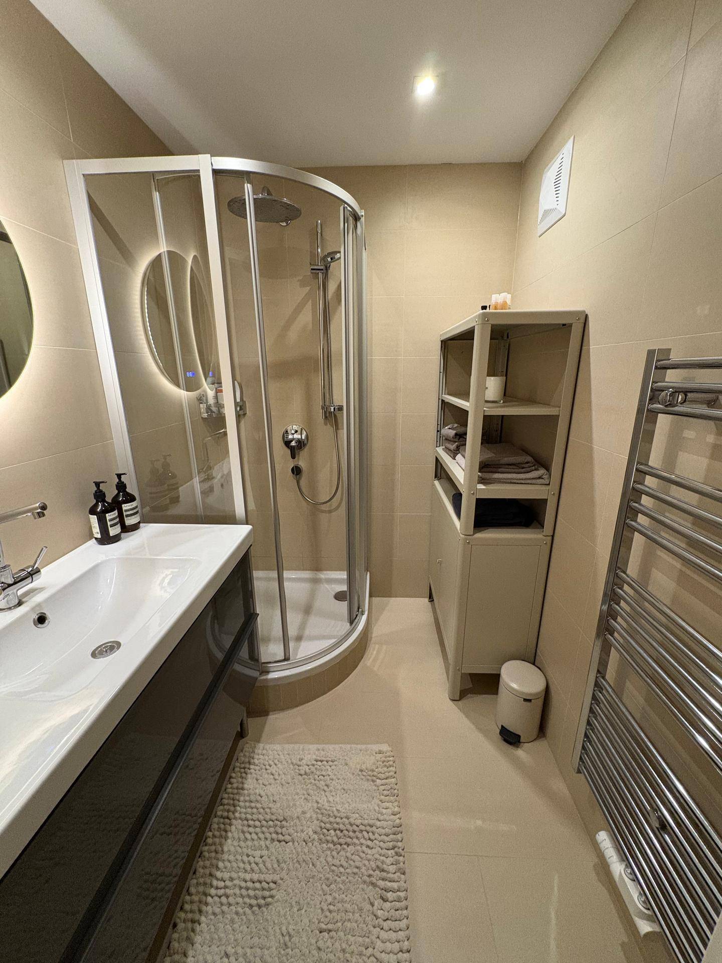 Modernes Badezimmer mit Duschkabine, Einzelwaschbecken und beheiztem Handtuchhalter.