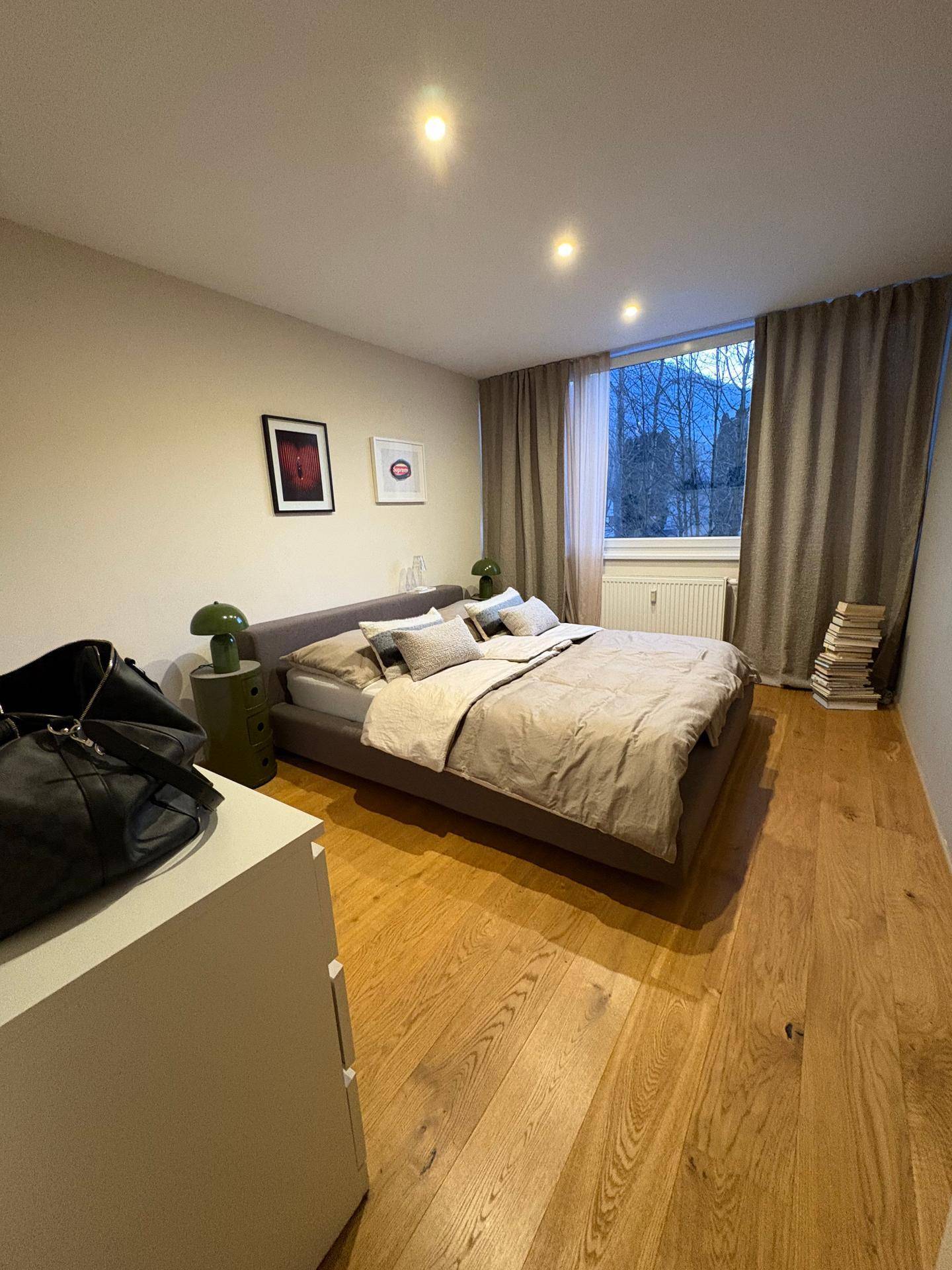Gemütliches Schlafzimmer mit Holzboden, großem Bett und Blick ins Grüne.