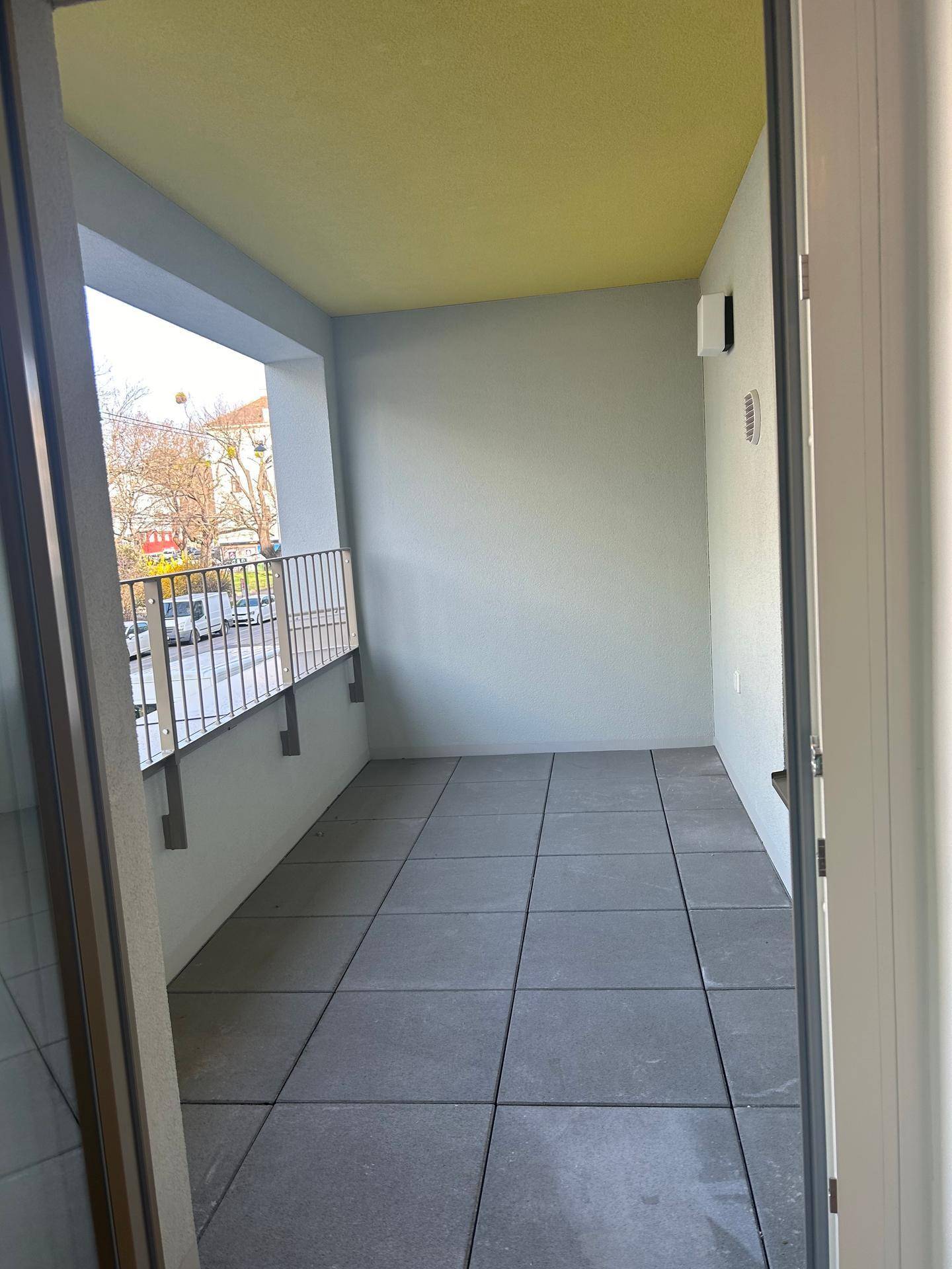 Geräumiger Balkon mit Fliesenboden und Blick auf die städtische Umgebung, ideal zum Entspannen im Freien.