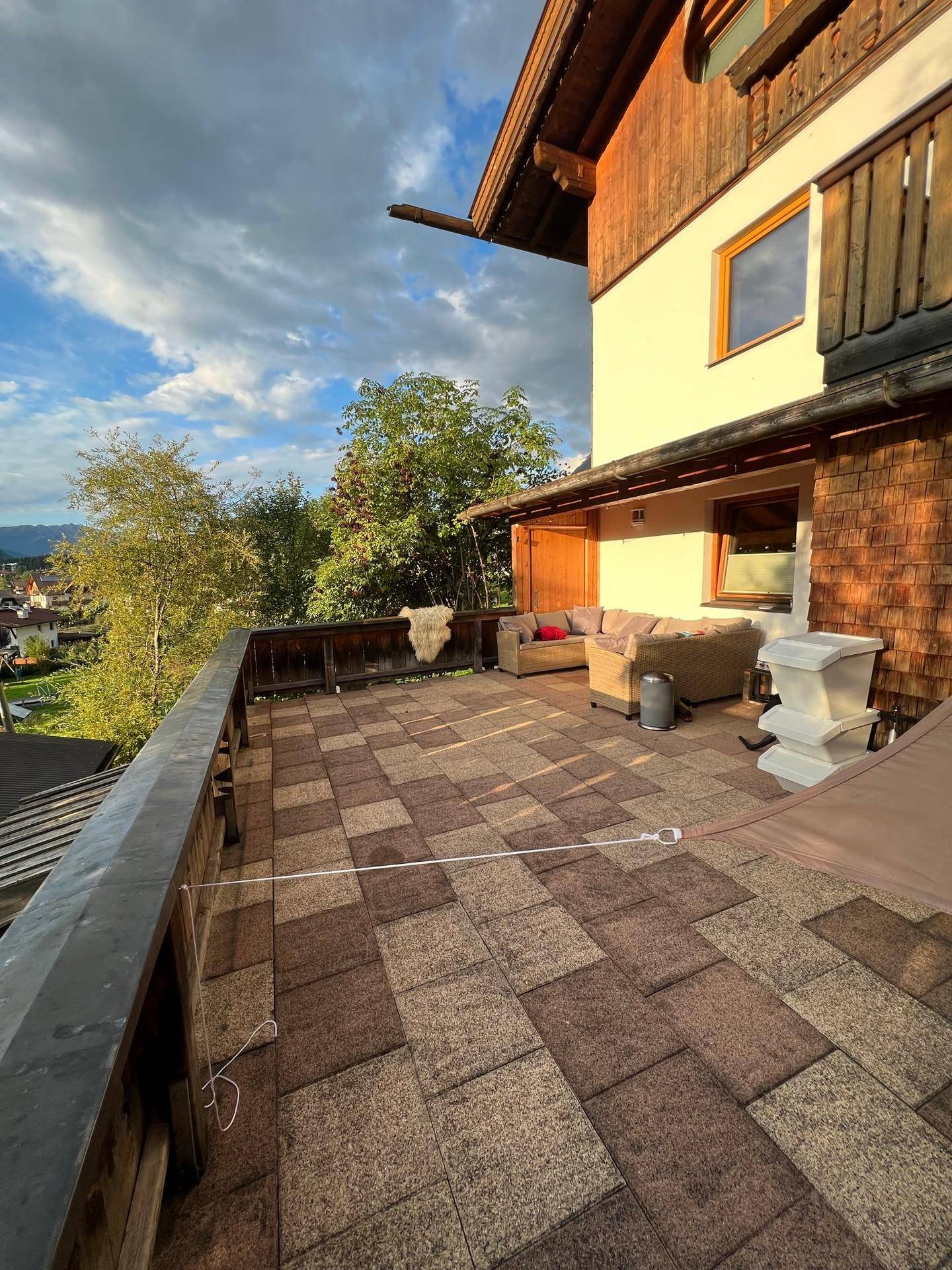 Weitläufige Terrasse mit Steinplatten und bequemen Outdoor-Möbeln, ideal zum Entspannen.