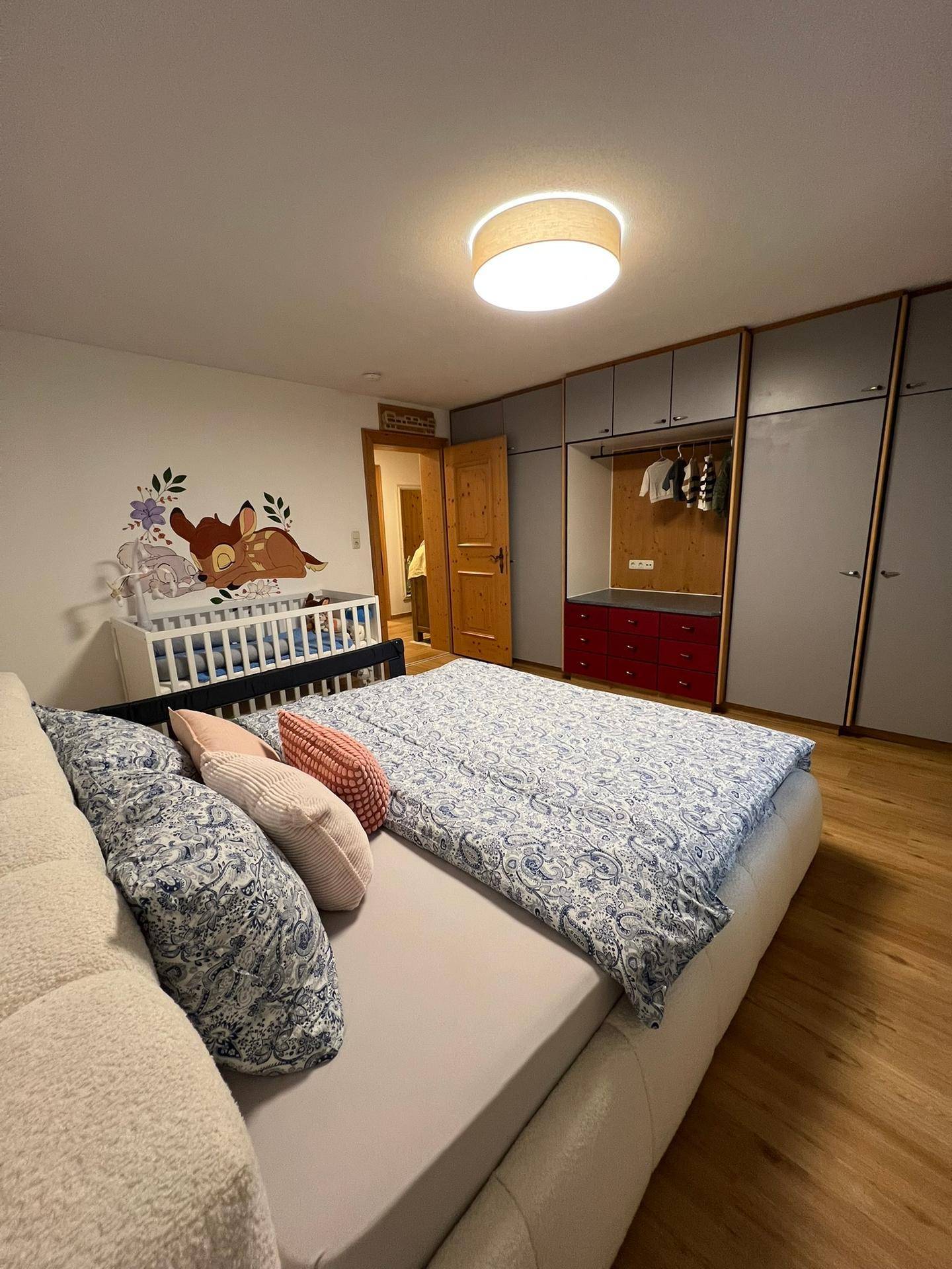 Schlafzimmer mit Doppelbett, Babybett und praktischen, modernen Einbauschränken.
