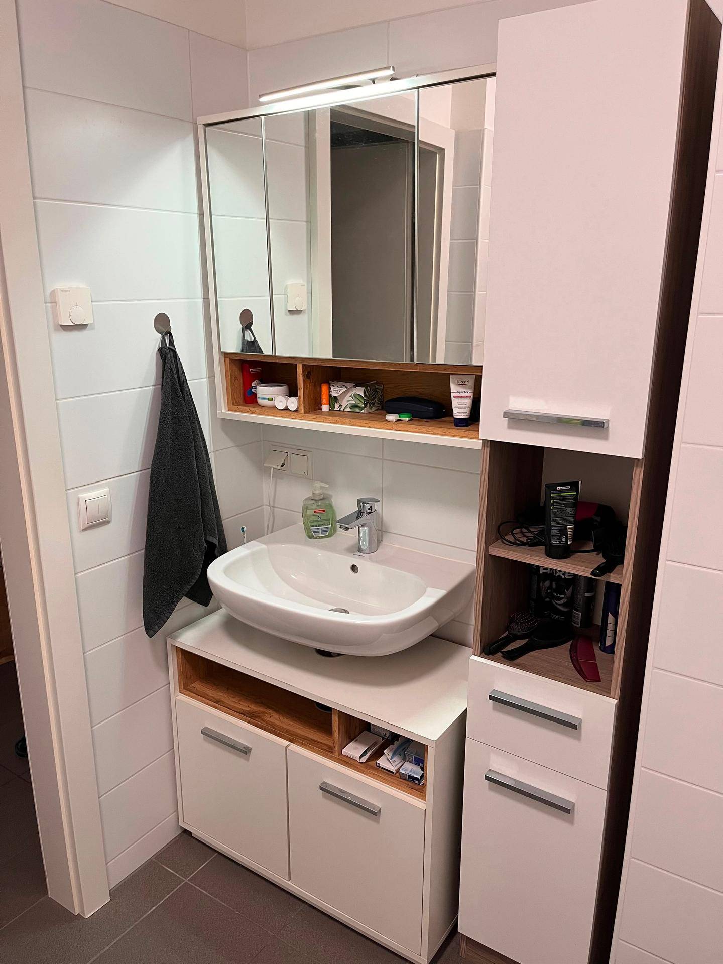 Detailansicht des Waschbeckens und Spiegelschranks im Badezimmer, mit praktischem Stauraum.