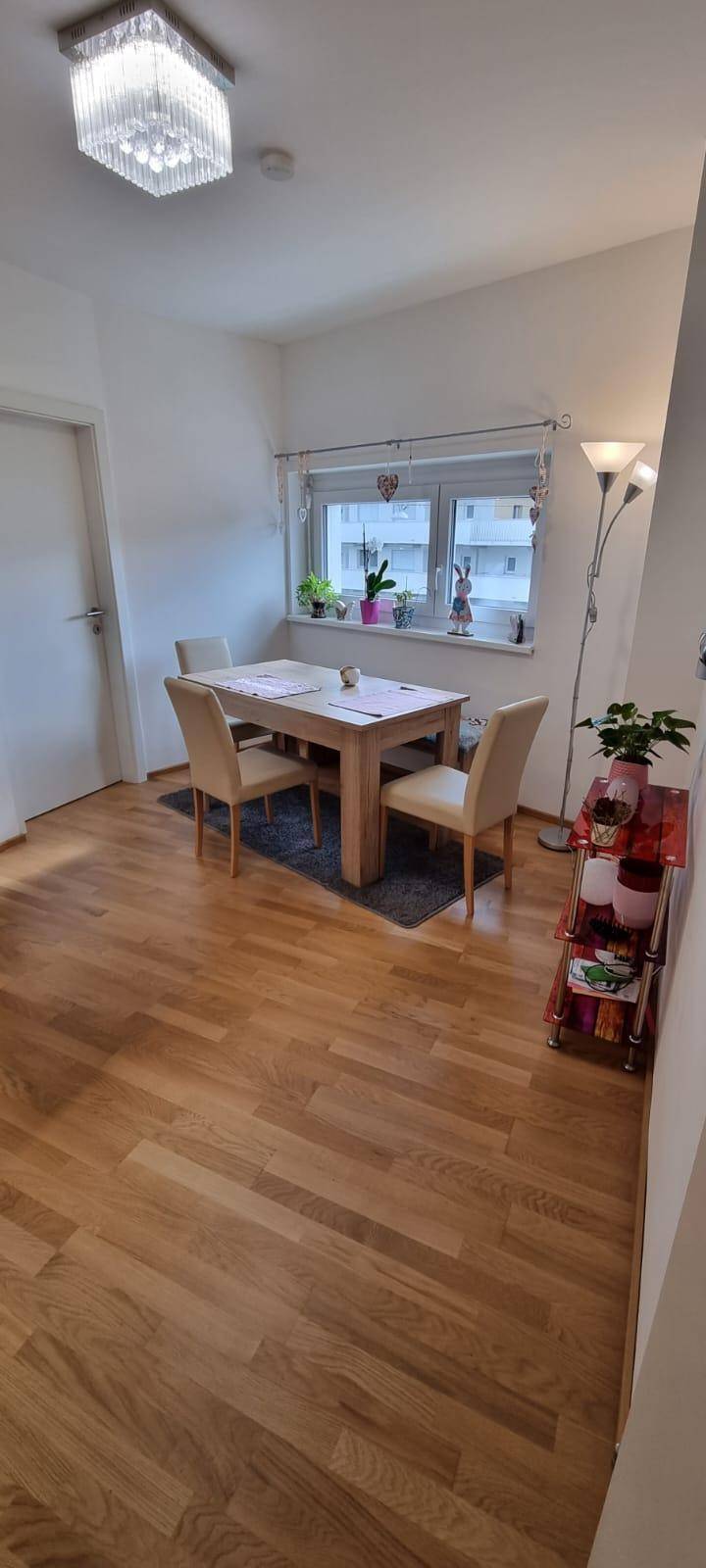 Gemütlicher Essbereich mit Holztisch und Stühlen, beleuchtet durch ein Fenster, ideal für Mahlzeiten.