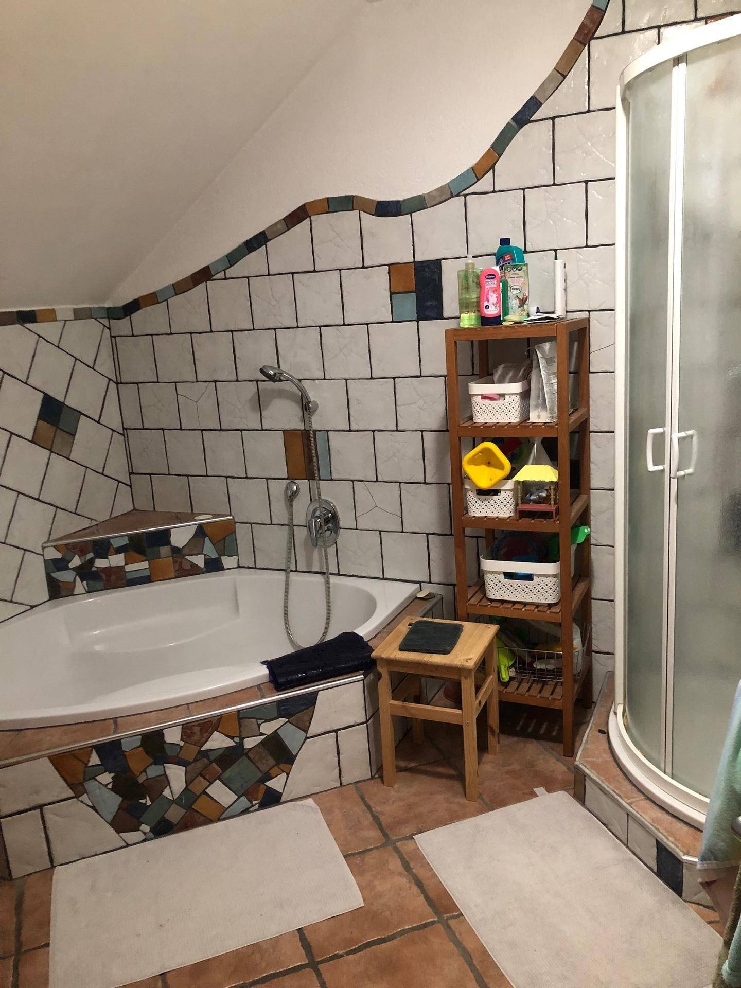 Badezimmer mit Eckbadewanne, Duschkabine und farbenfrohen Fliesen im Dachgeschoss.